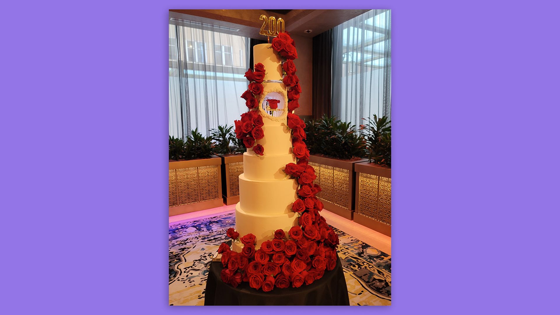 large tiered white cake covered in red roses