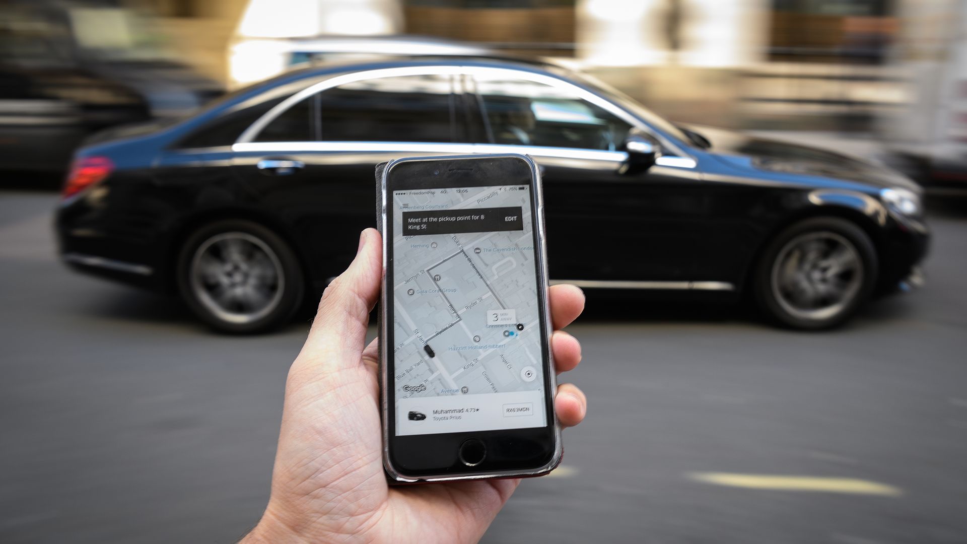Outstretched hand holds phone with Uber app open