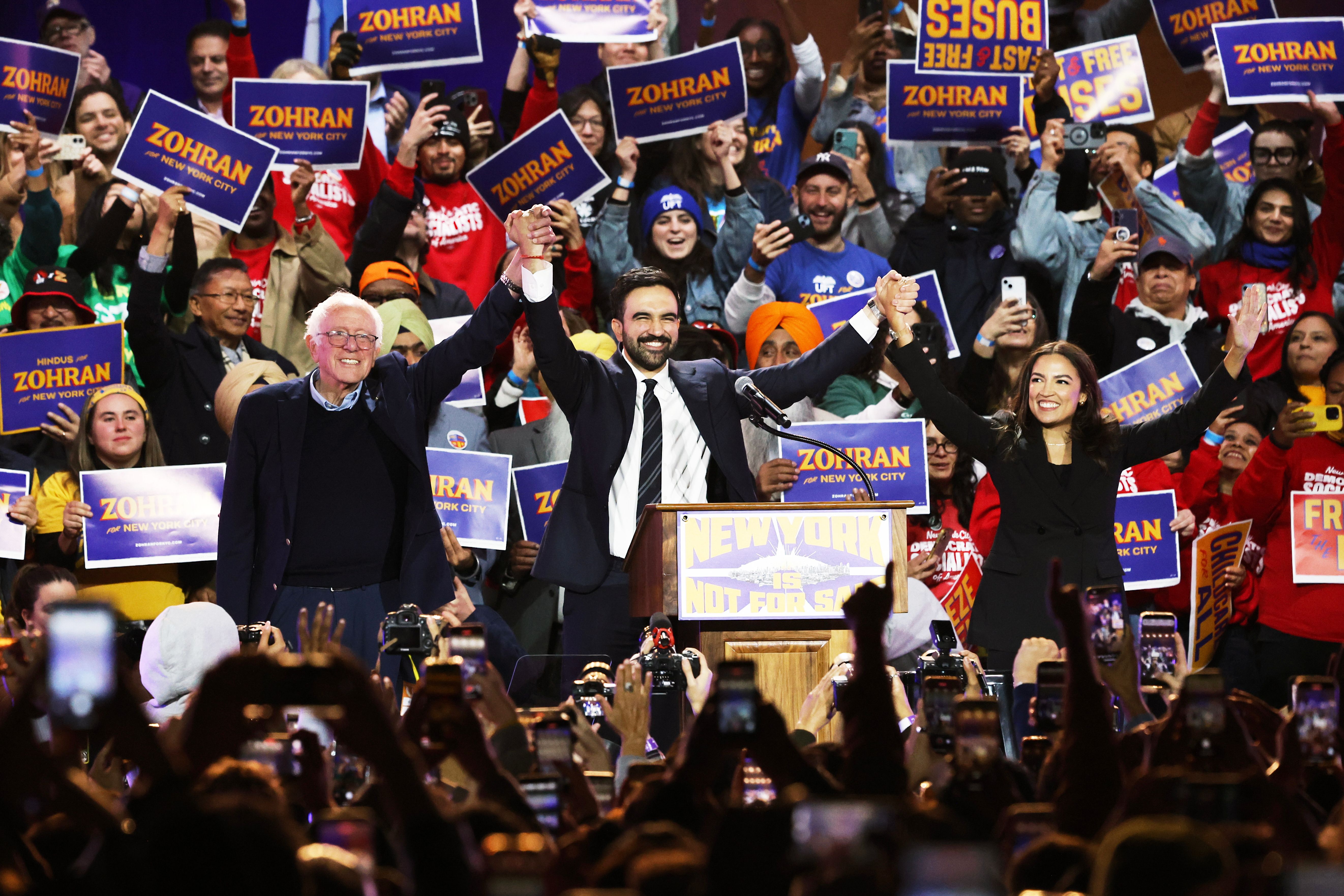 New York mayoral favorite Zohran Mamdani is flanked by Sen. Bernie Sanders (I-Vt.) and Rep. Alexandria Ocasio-Cortez (D-N.Y.) on Sunday at Forest Hills Stadium in Queens. Photo: Heather Khalifa/AP