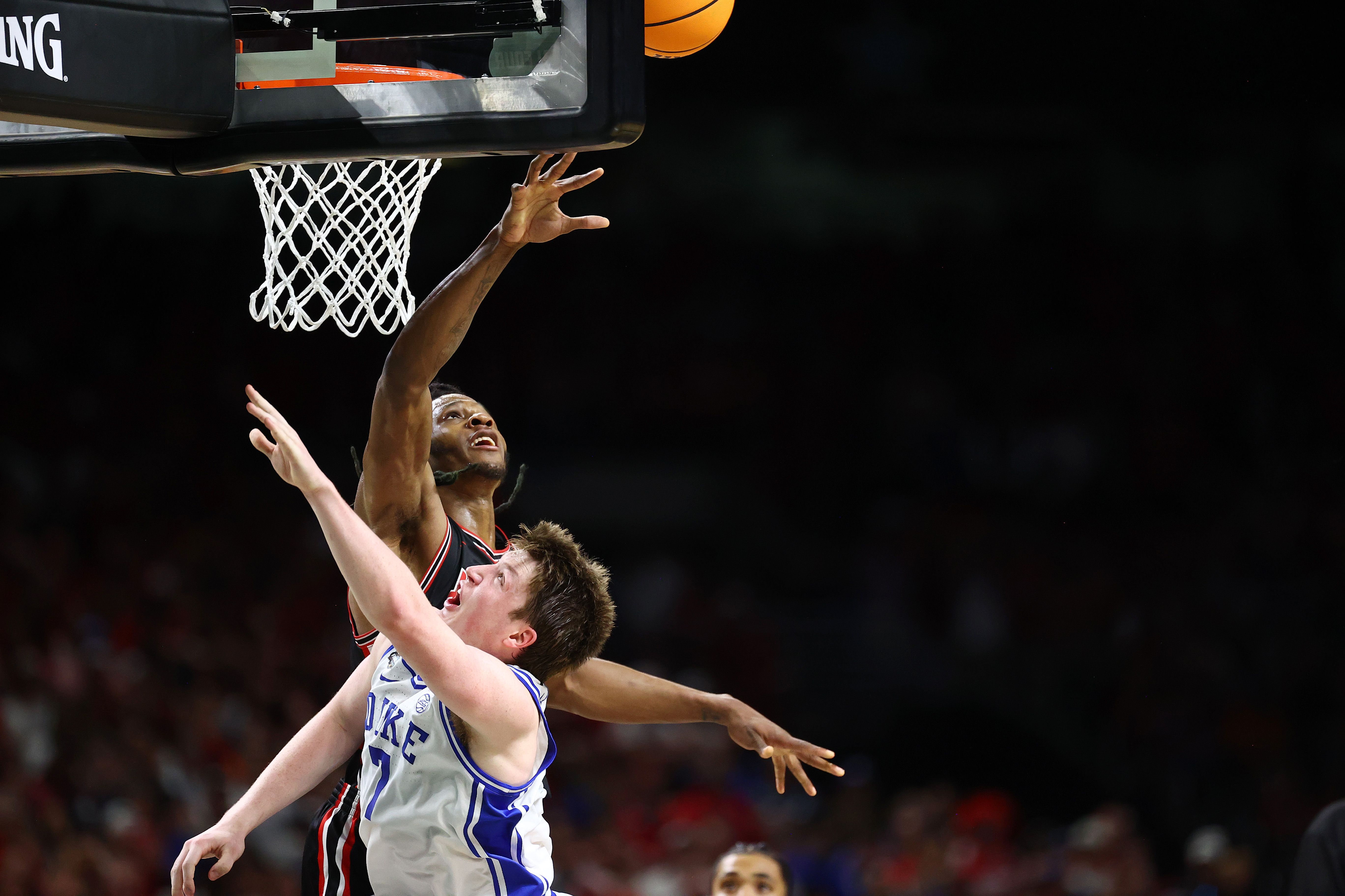 Joseph Tugler #11 of the Houston Cougars reaches for the ball above the basket at the same time as a Duke player.