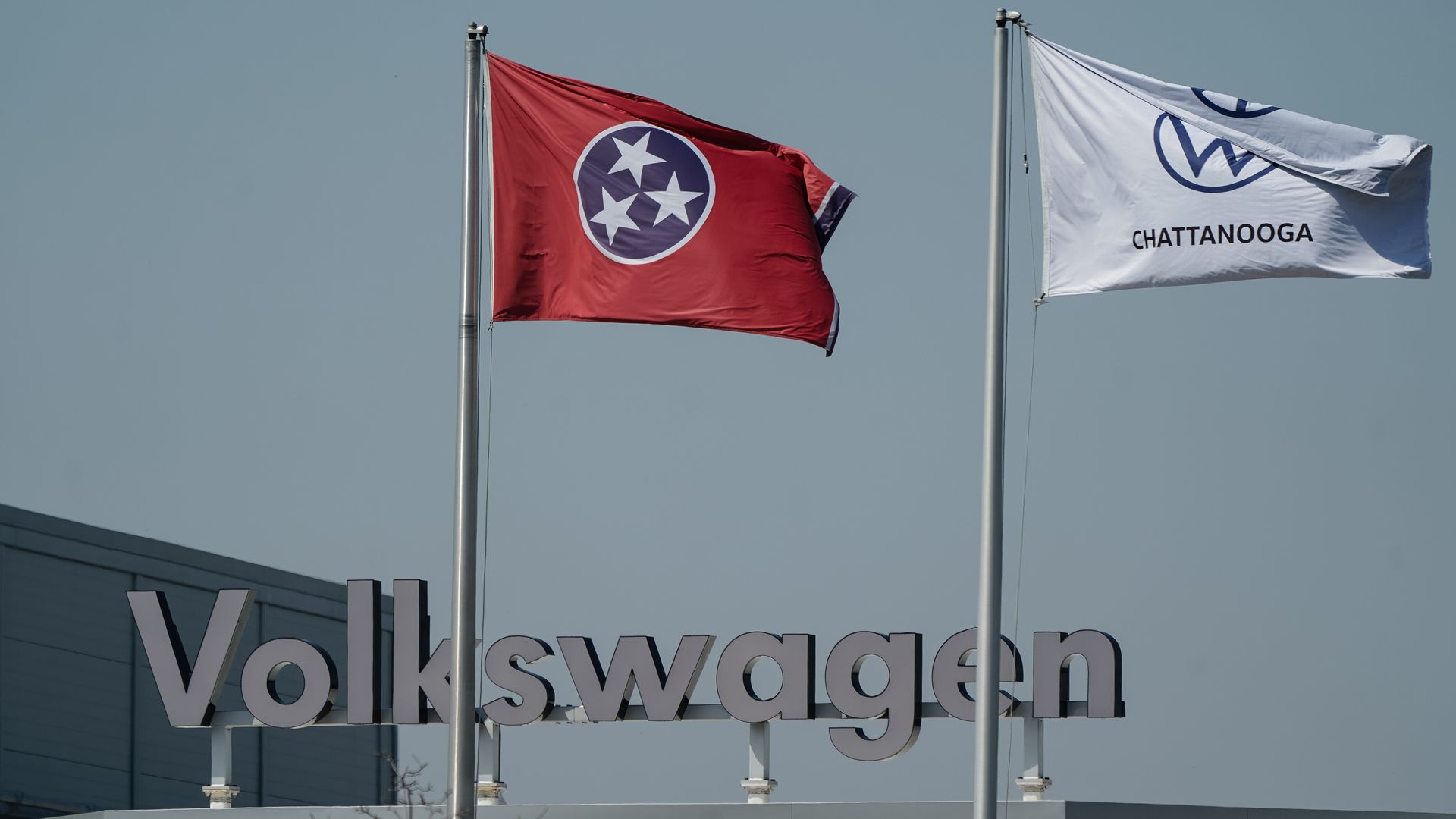 Flags flying over a factory with the sign of Volkswagen