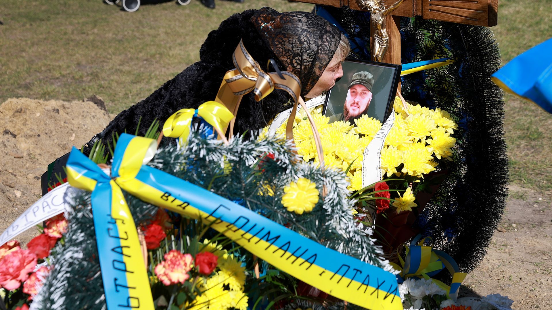 A Ukrainian woman is seen kissing a photo of her son at his grave after he died while fighting the Russians.
