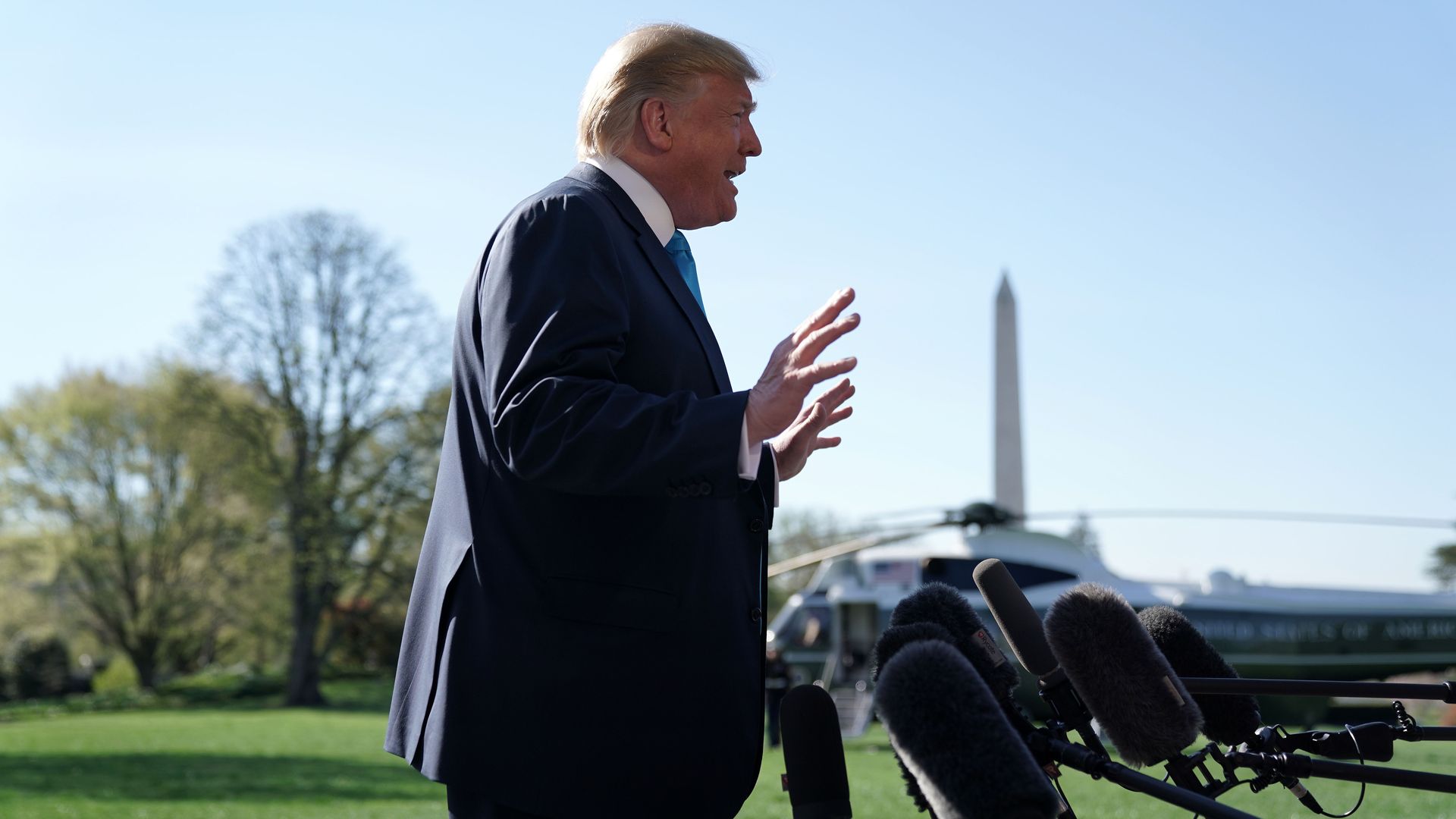President Trump speaks into microphones with the Washington monument behind him.