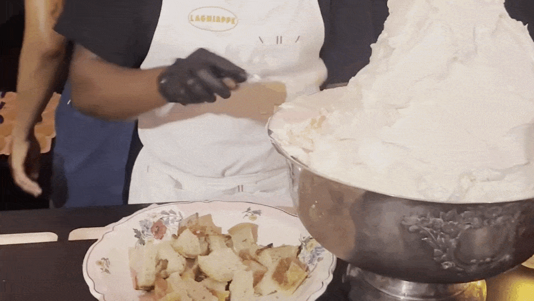 A zoomed in video as someone scoops up butter out of a giant silver urn and slathers it onto some toast.