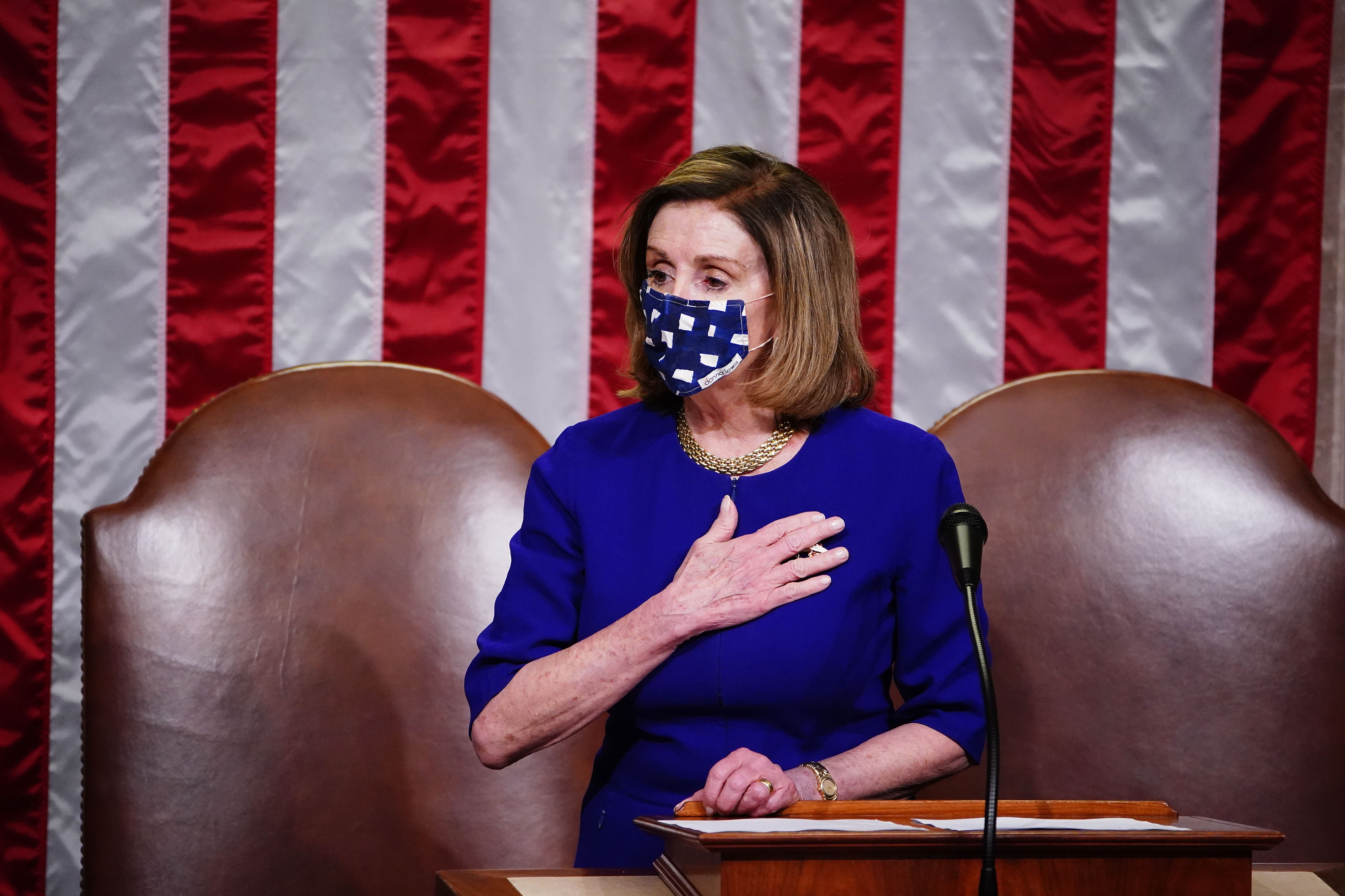 Nancy Pelosi speaks, wearing blue, at the rostrum as Congress reconvenes on Jan. 6, 2021, following a breach of the Capitol by a pro-Trump mob.
