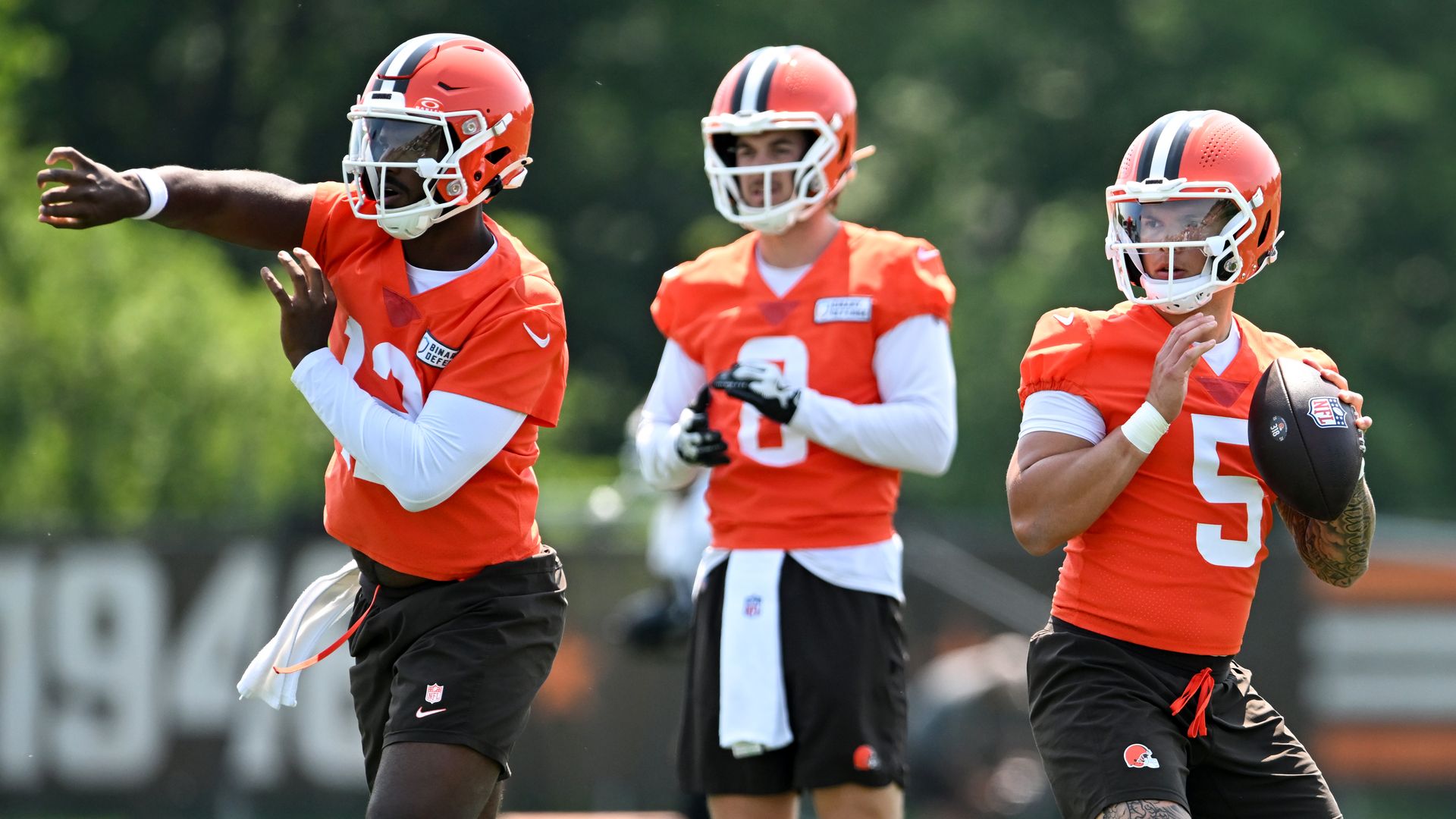 Shedeur Sanders, Kenny Pickett and Dillon Gabriel of the Cleveland Browns run a drill in practice jerserys and shorts.