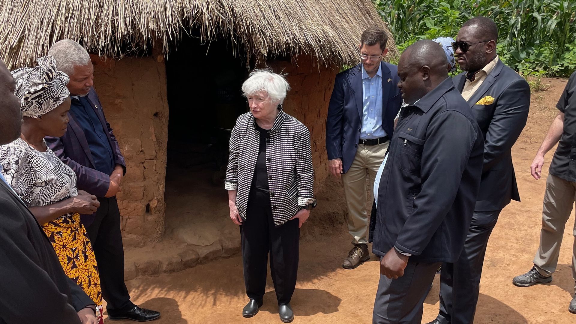 Janet Yellen stands before a hut
