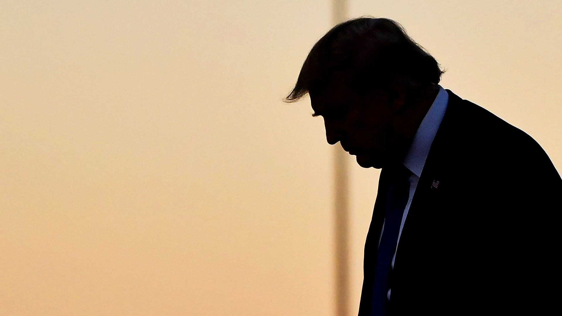 Donald Trump in silhouette before orange sky looks down