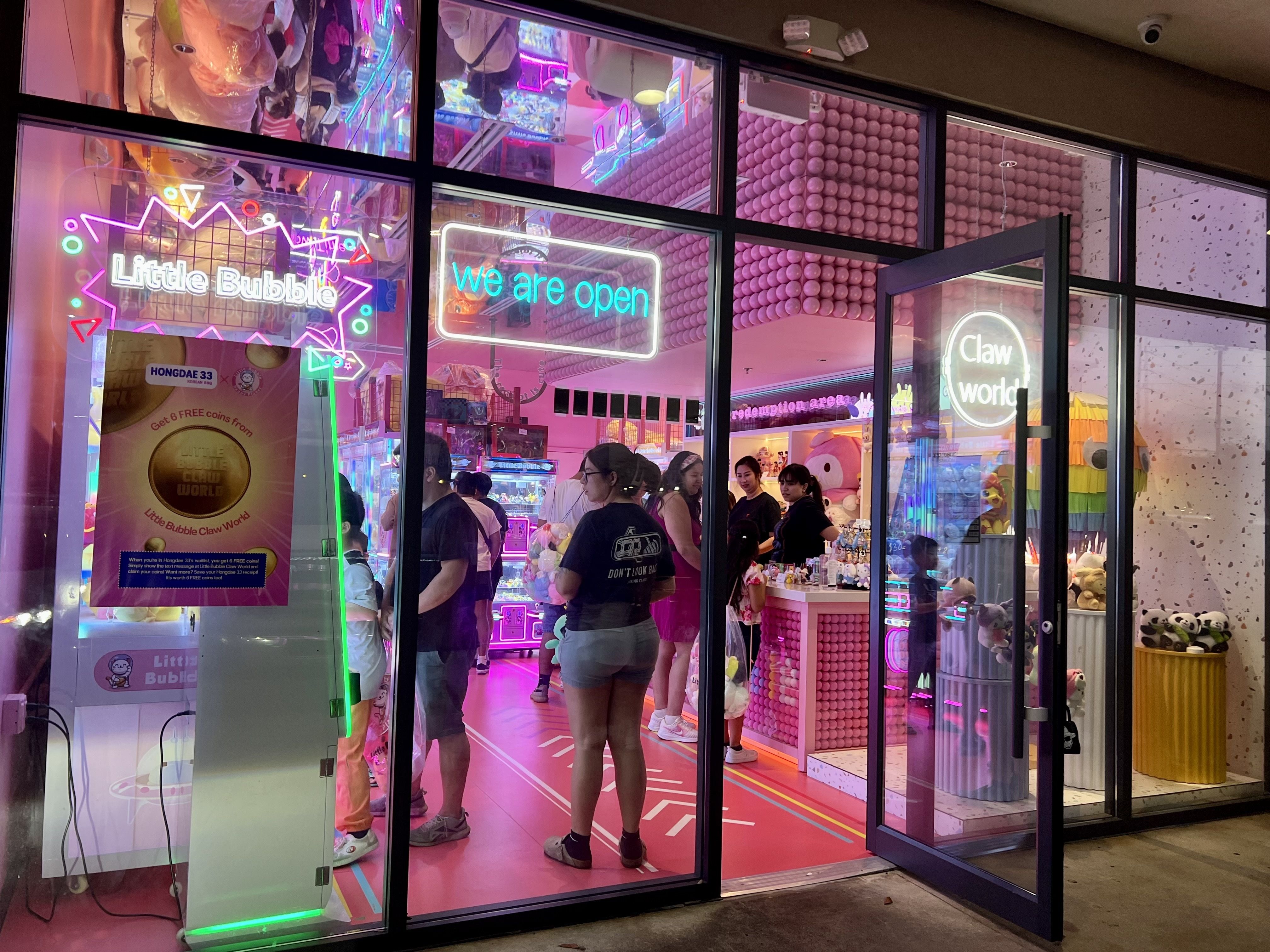 Photo of the outside of a claw machine arcade, with the pink hue peaking out. 