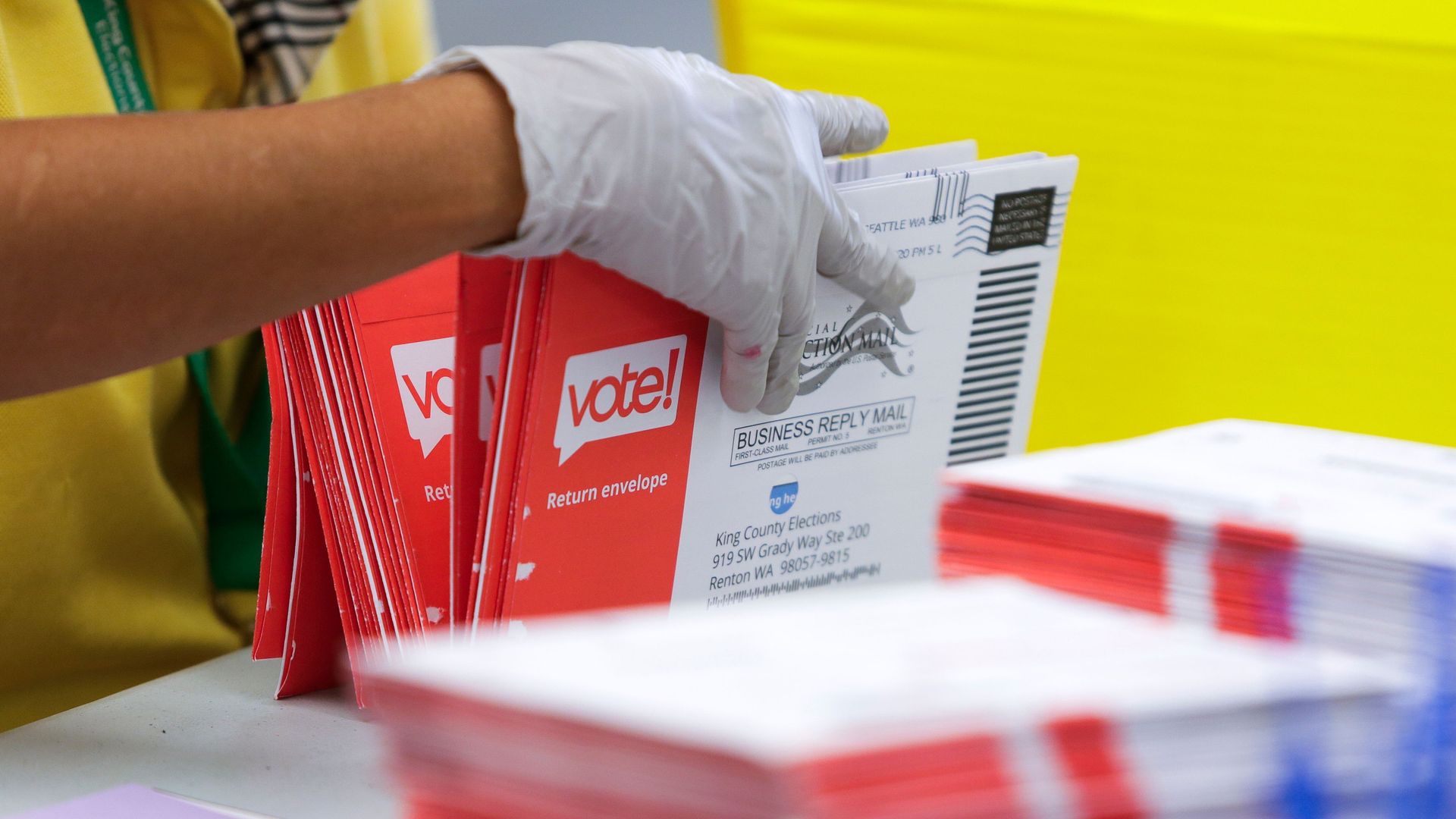 Gloved hand holding stacks of ballots