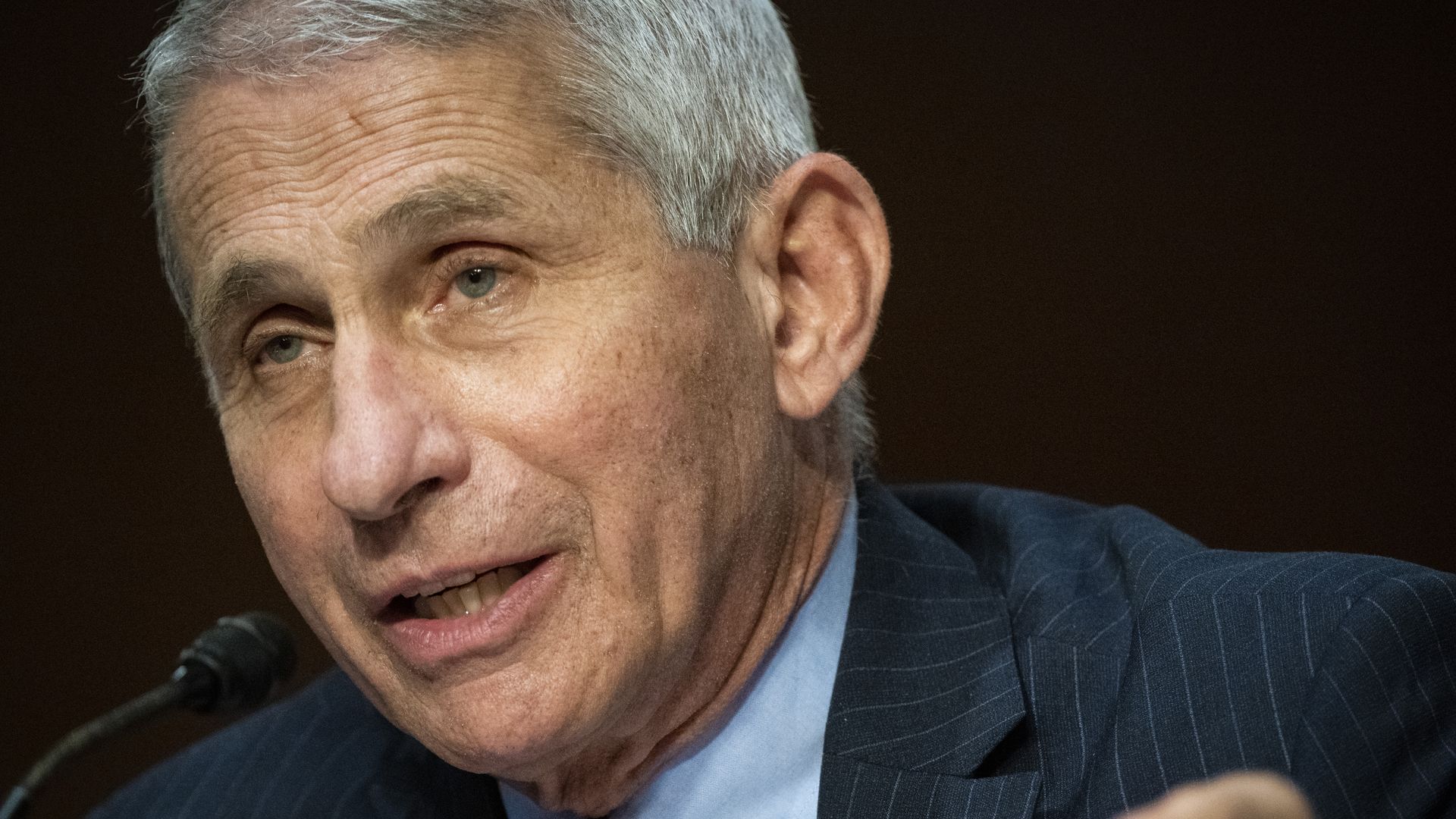 Fauci sits and wears a suit and tie