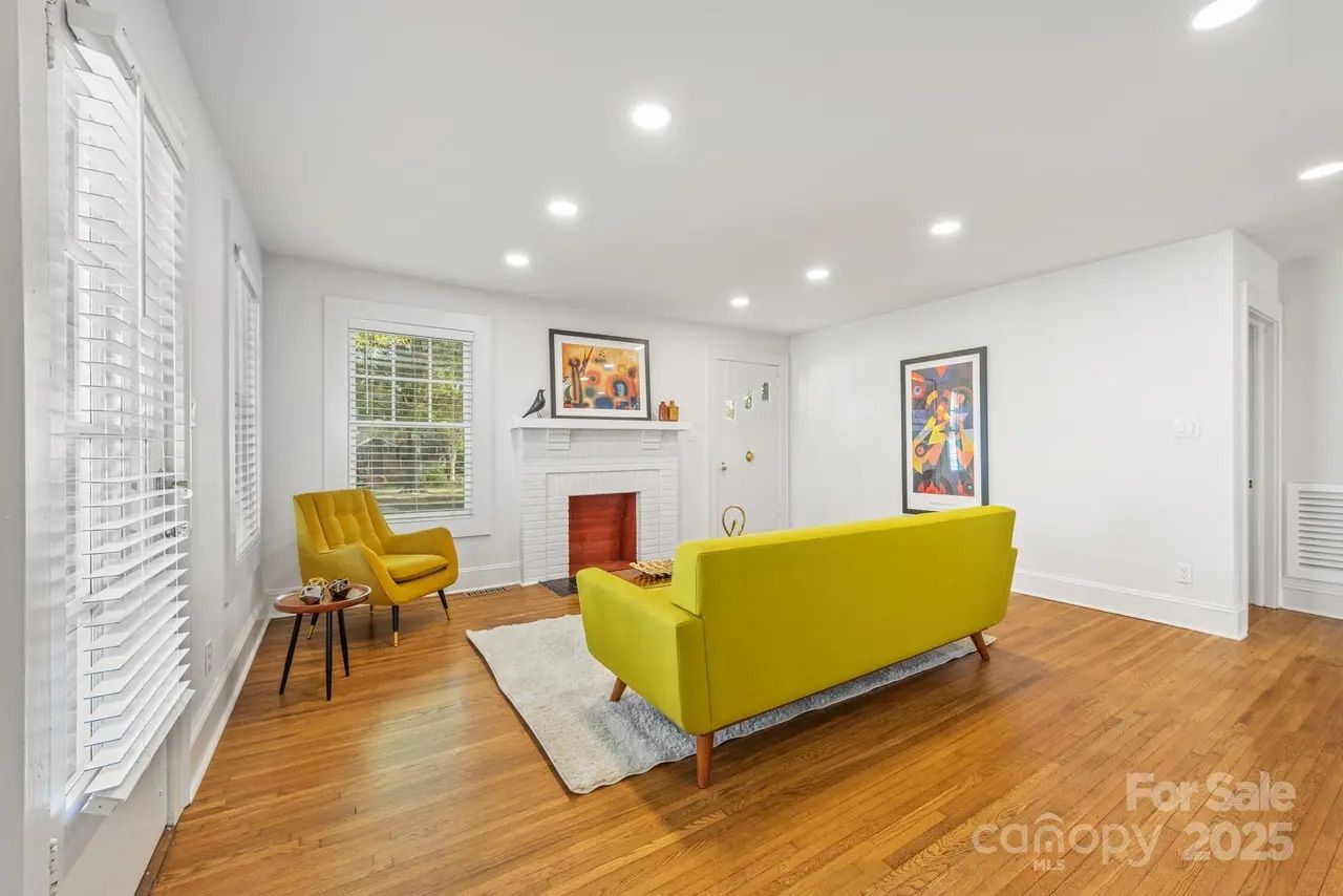 Backyard with large wooden deck and built-in benches, green trees, and a blue playhouse with white trim and double doors under a clear sky.