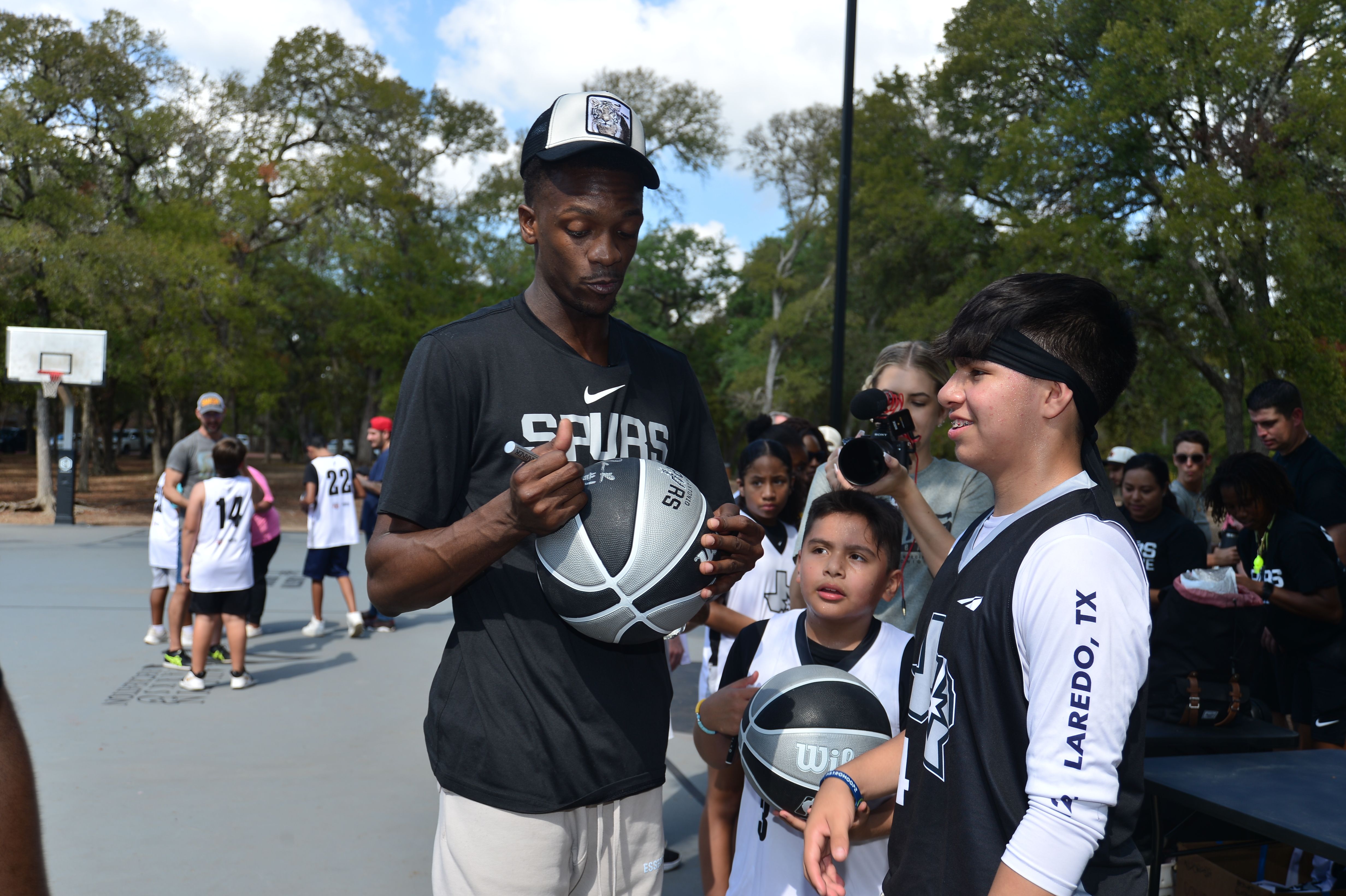 A Spurs basketball player signs a ball in Austin.