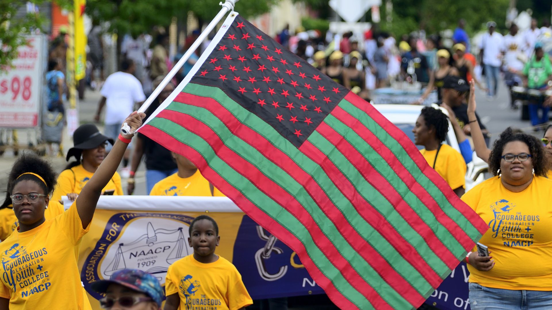 Elected officials, community leaders, youth and drum and marching bands take part in the second annual Juneteenth Parade, in Philadelphia while holding a red and green American flag