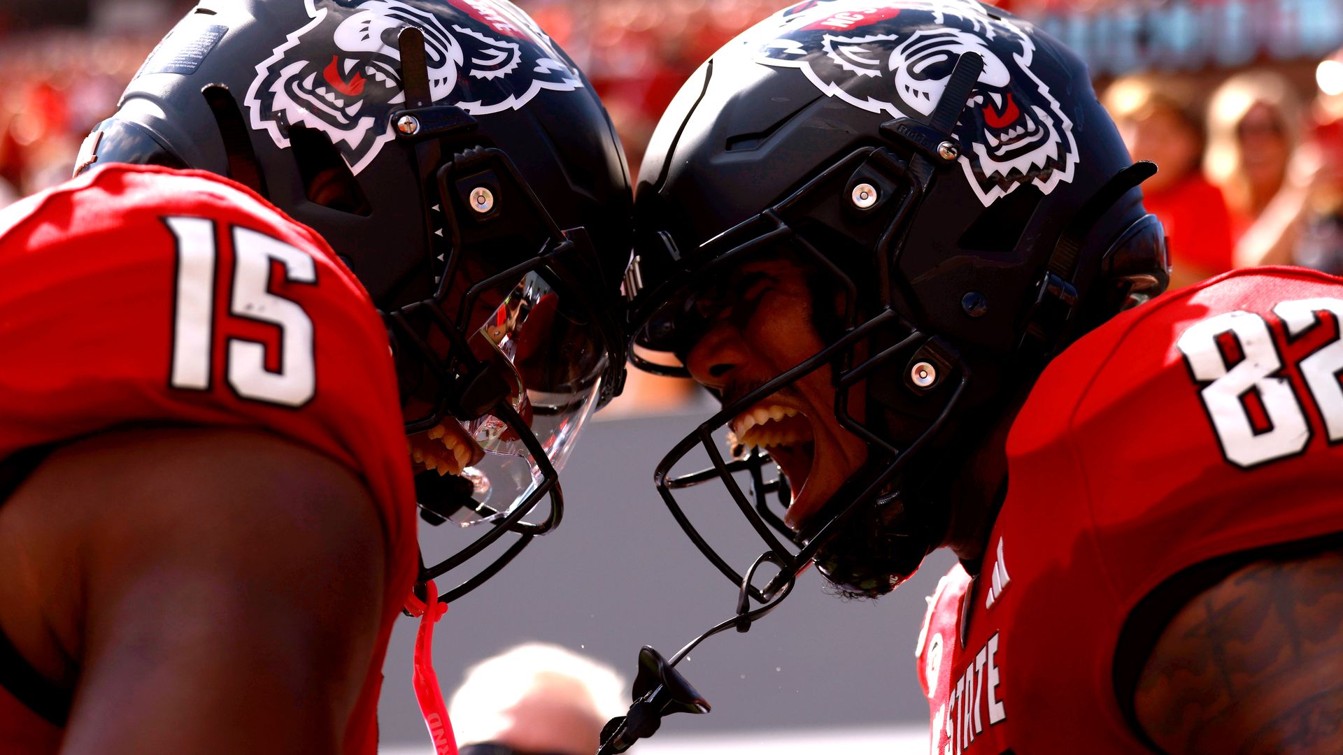 Two N.C. State players celebrate a touchdown by pressing their helmets together
