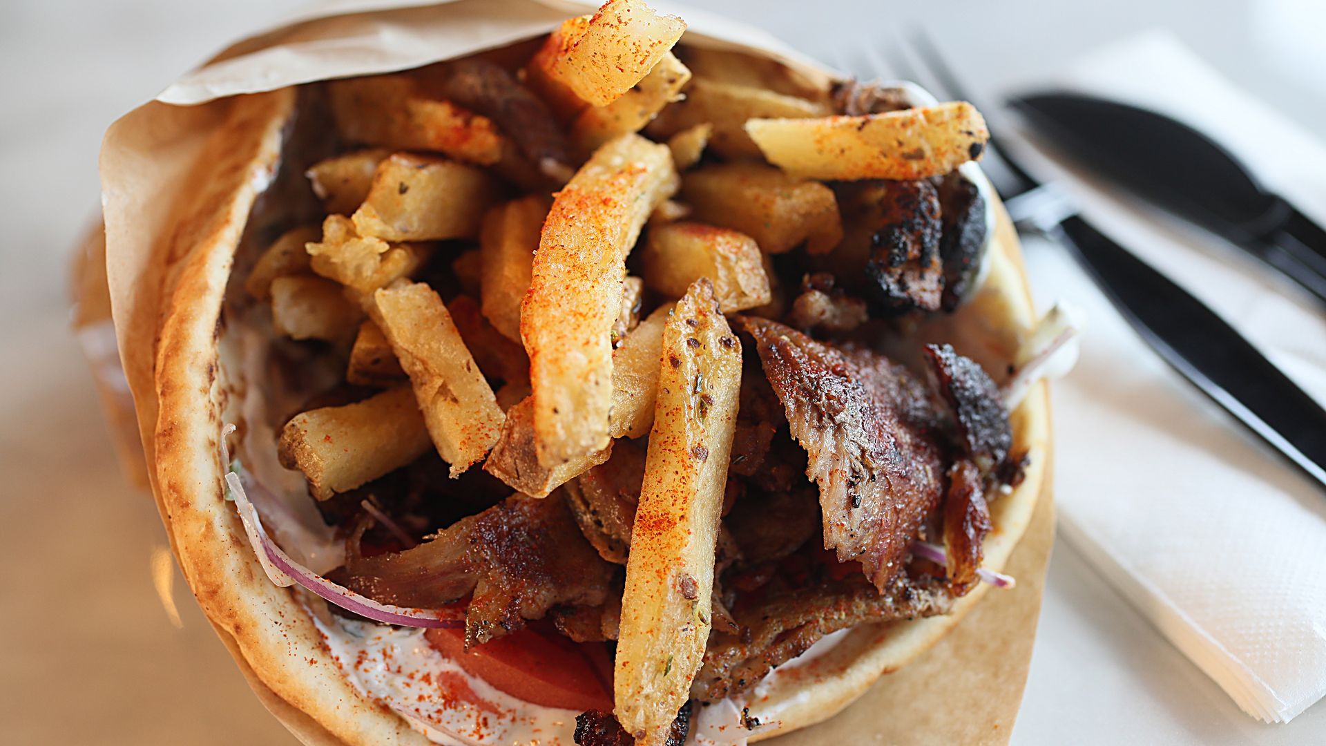 A gyro is shown as a pita wrap stuffed with meat and french fries.