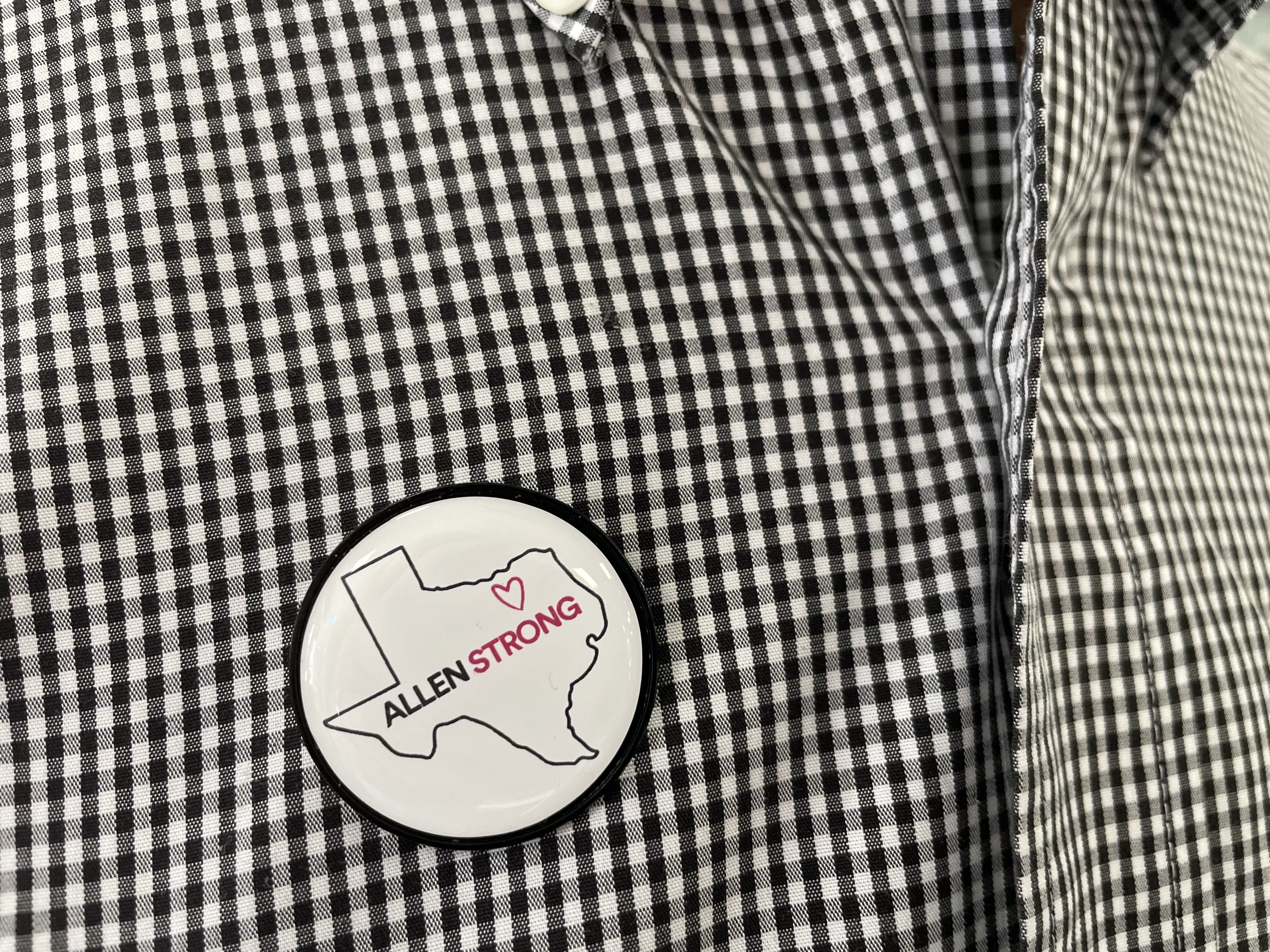 A button on a shirt. The button reads "Allen Strong."