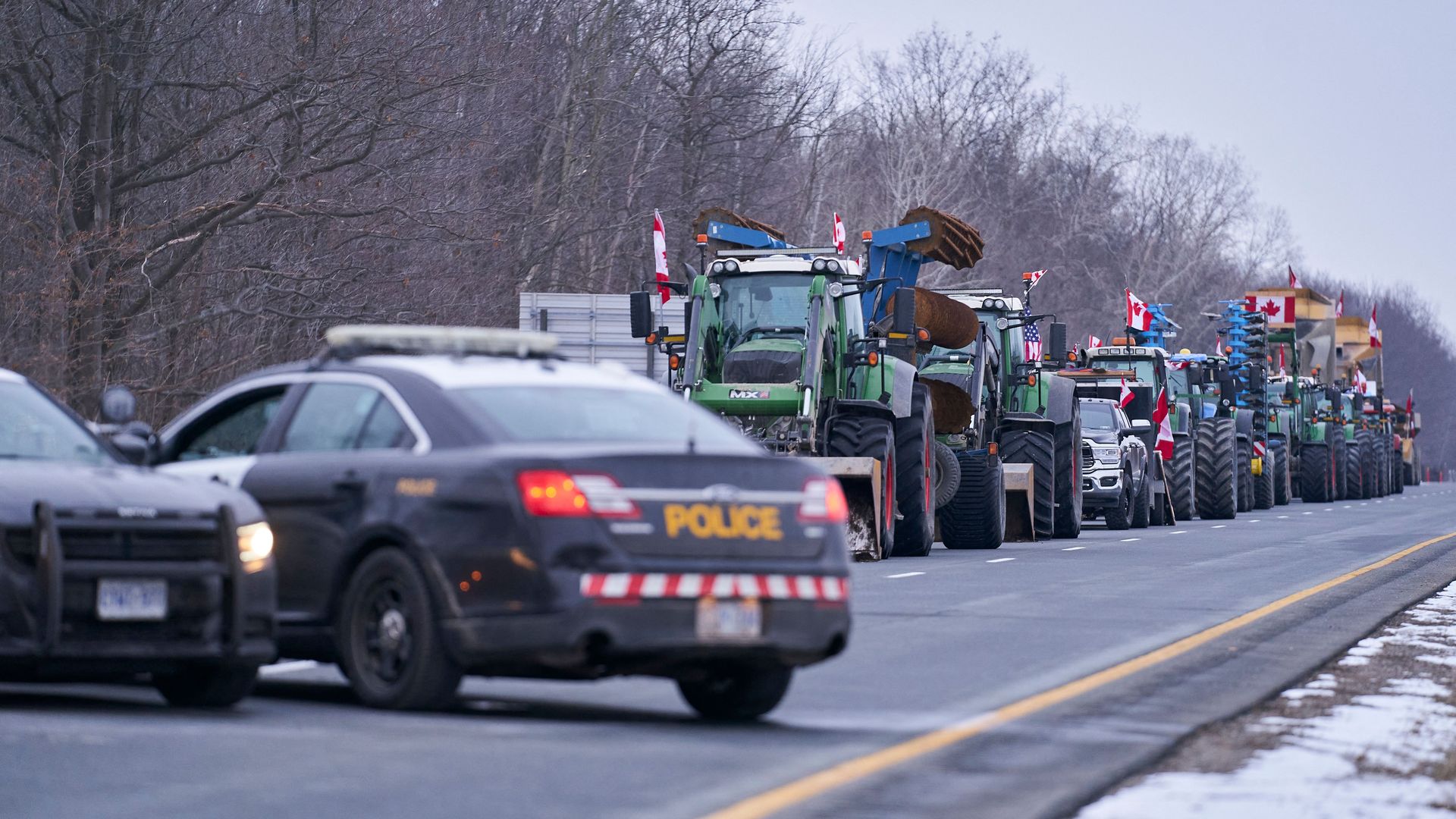 Picture of farm trucks blocking a road and two police cars parked in front of them