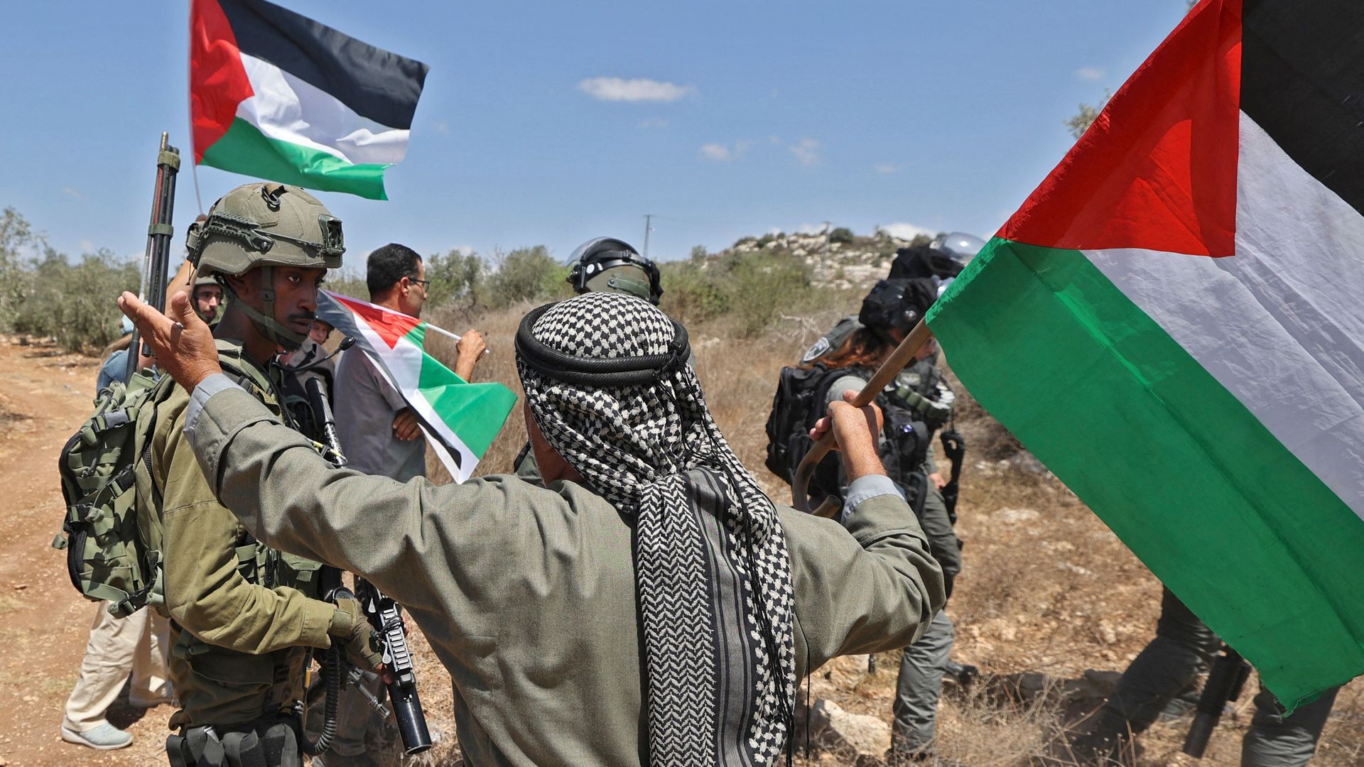 A protester waves Palestinian flags in front of Israeli soldiers in the village of Beit Lid in the occupied West Bank on Aug. 26. Photo: