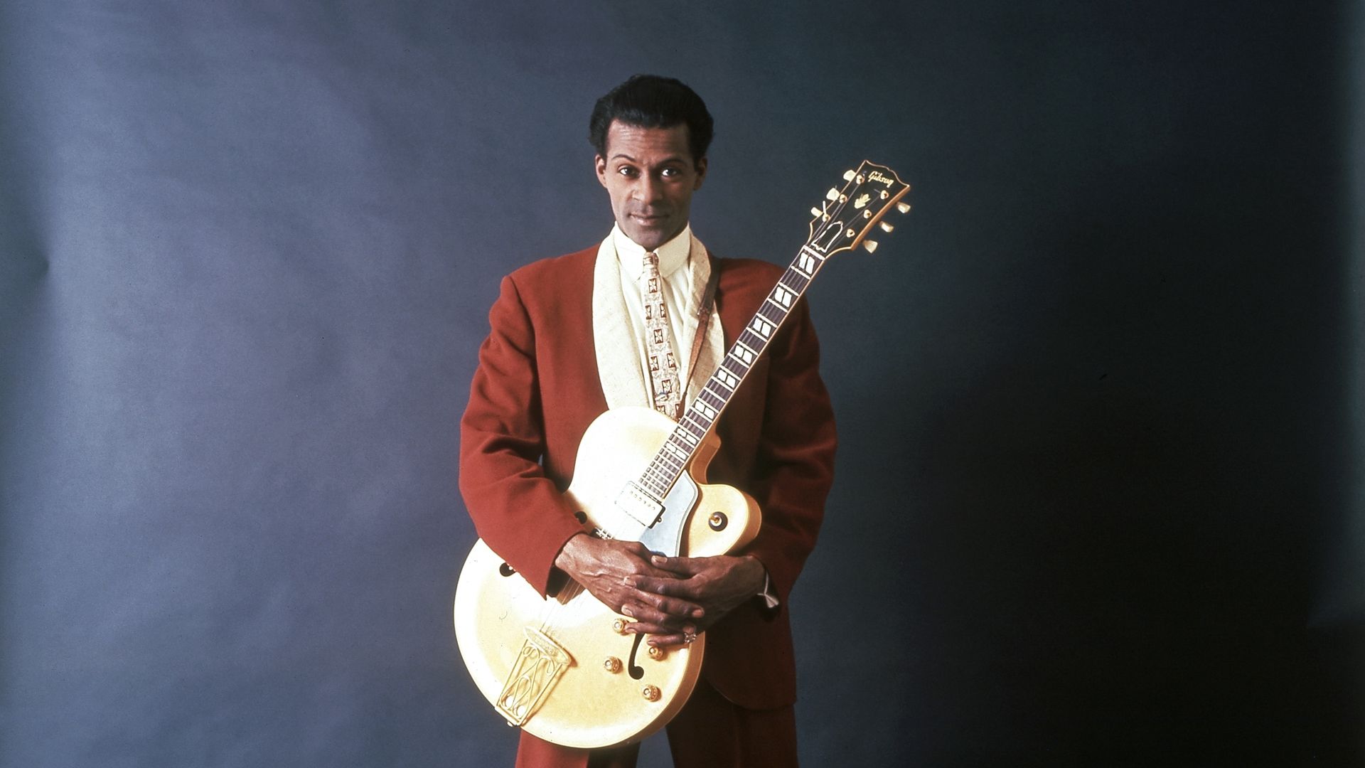 Chuck Berry poses for a picture in a red suit.