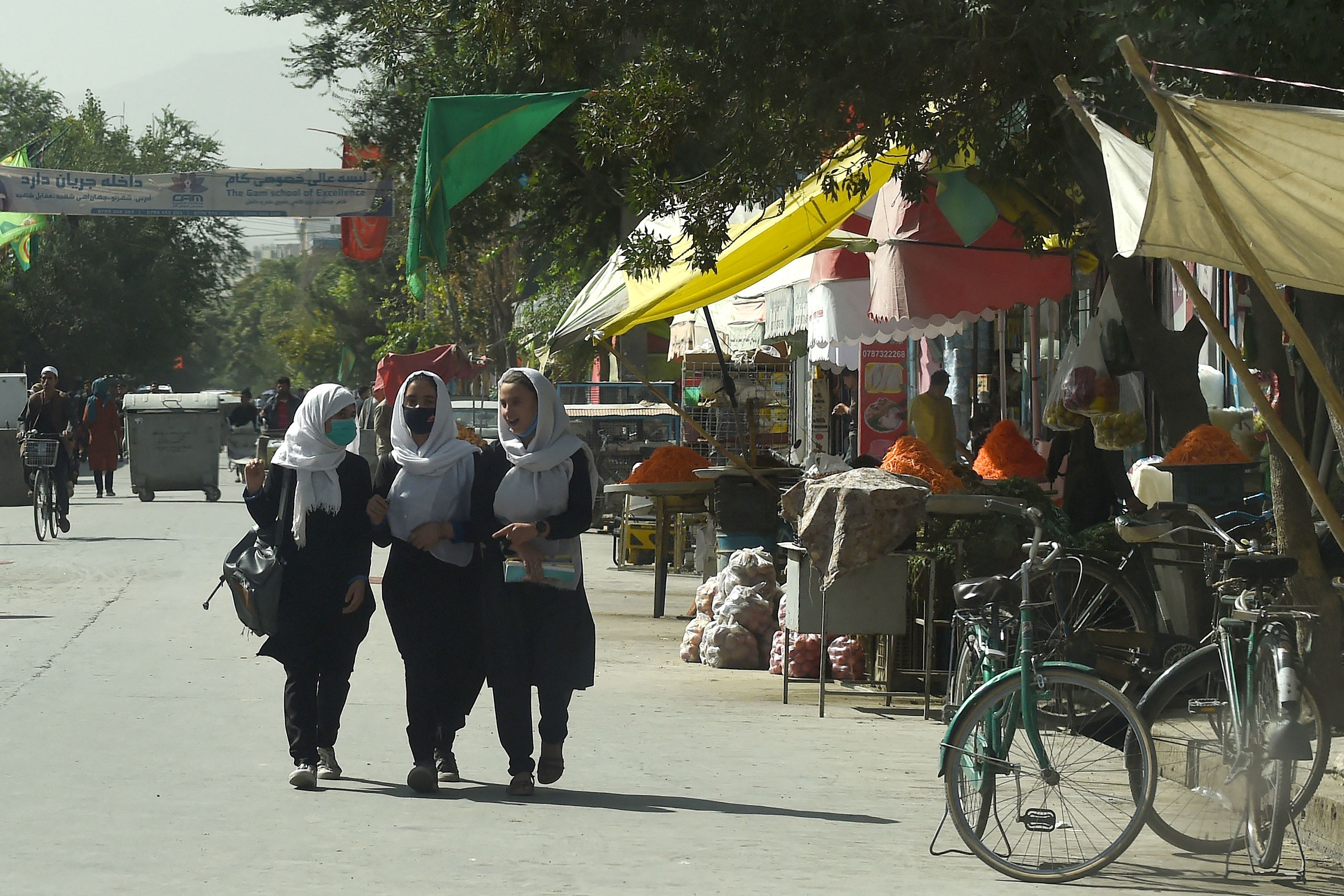 Afghan school girls walk through in a street in Kabul on August 15
