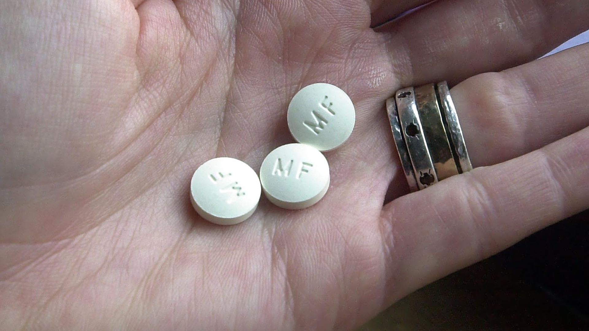 Photo of an open hand with three white pills sitting in the middle