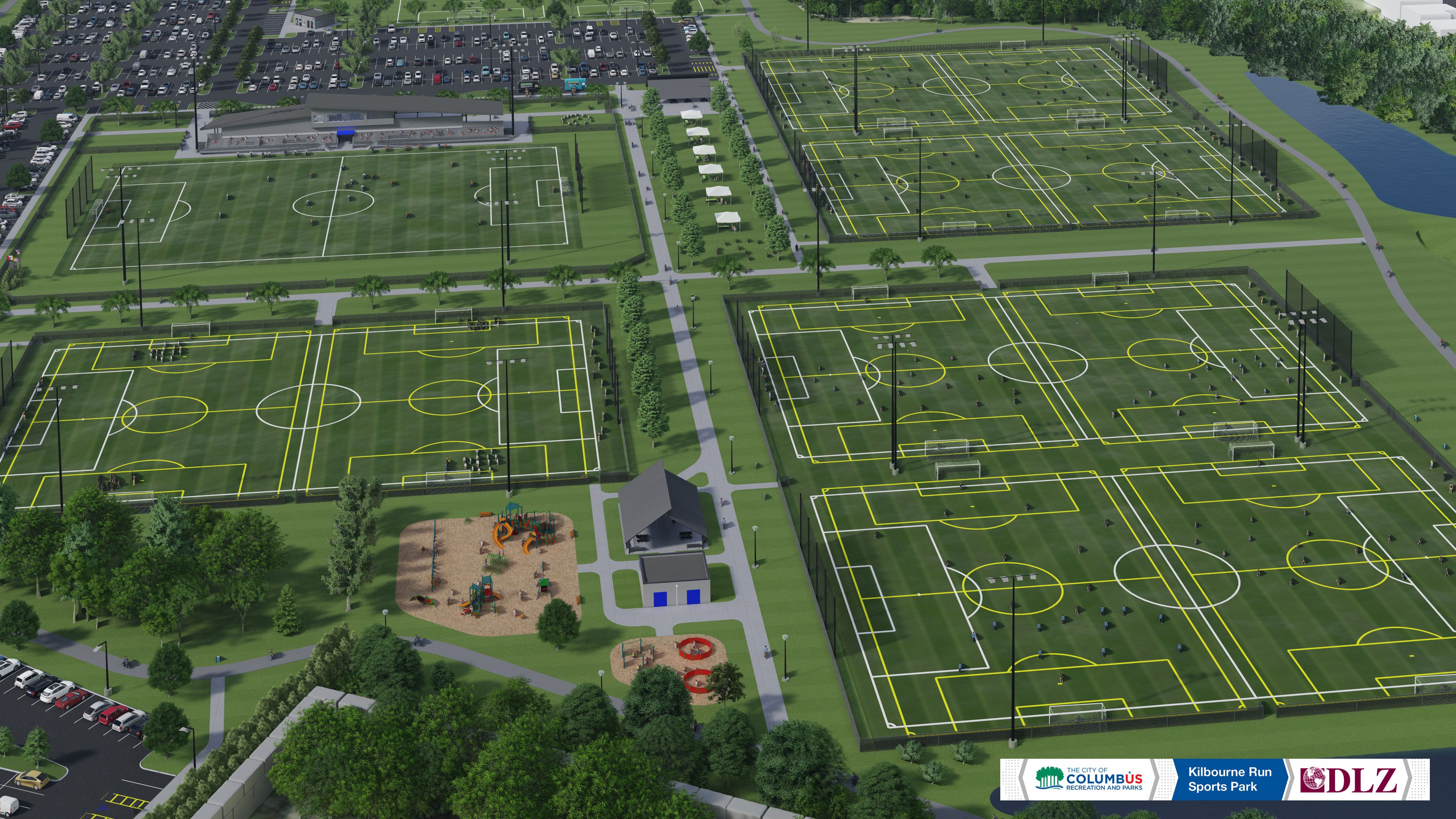 Aerial view of Kilbourne Run Sports Park with multiple soccer fields marked in yellow and white lines, a playground, parking lots, trees, and pathways with buildings and river nearby.