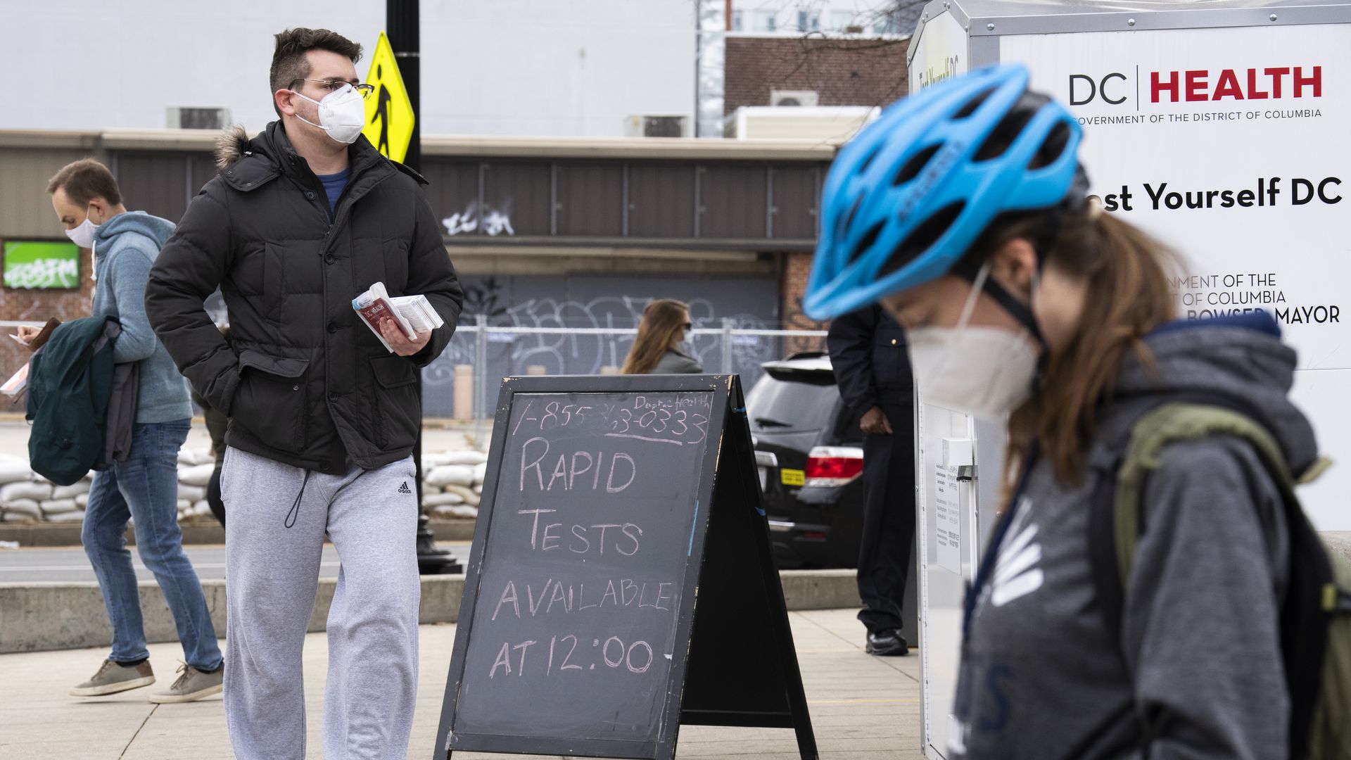 Picture of people walking and a sign that says there are COVID-19 rapid tests available