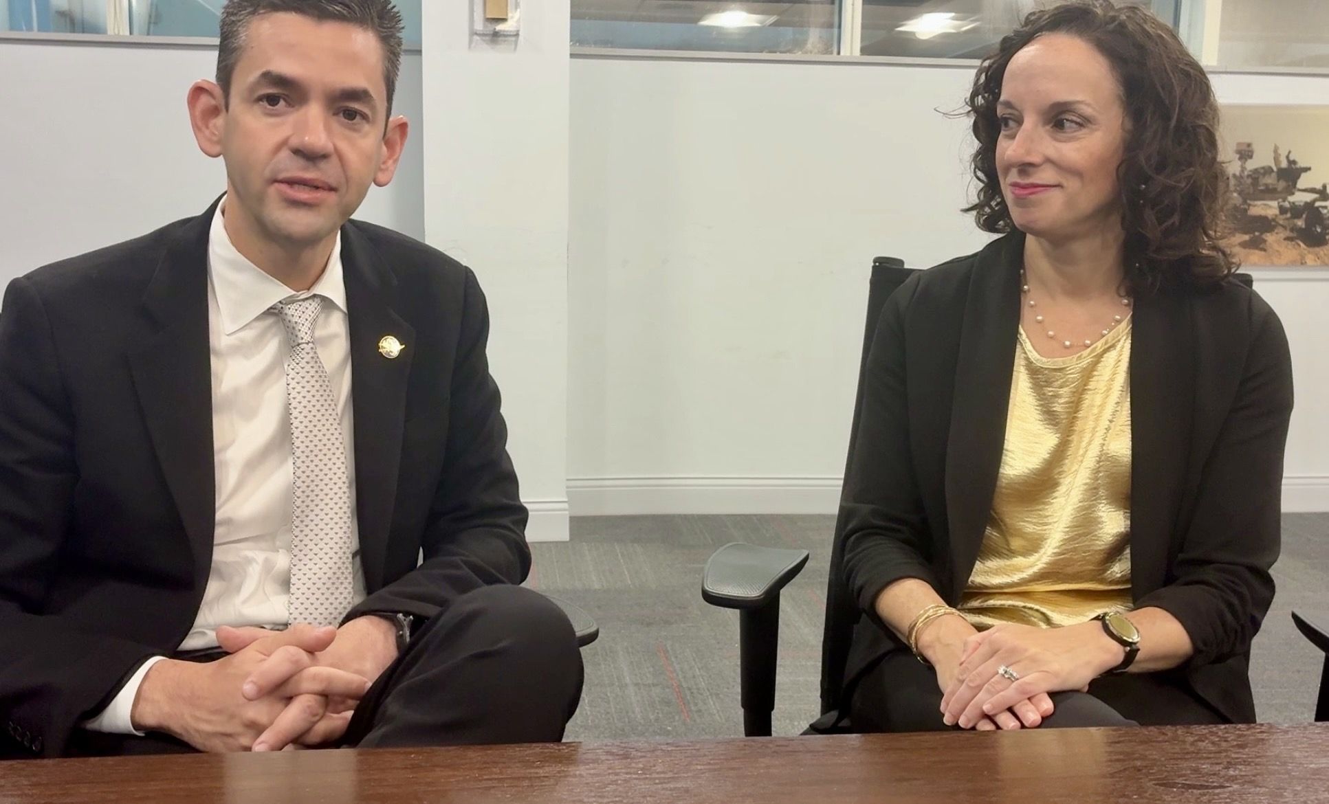 NASA administrator Jared Isaacman (left) sits next to Rockedyne CEO Kristin Houston (right) at a long table in a conference room.