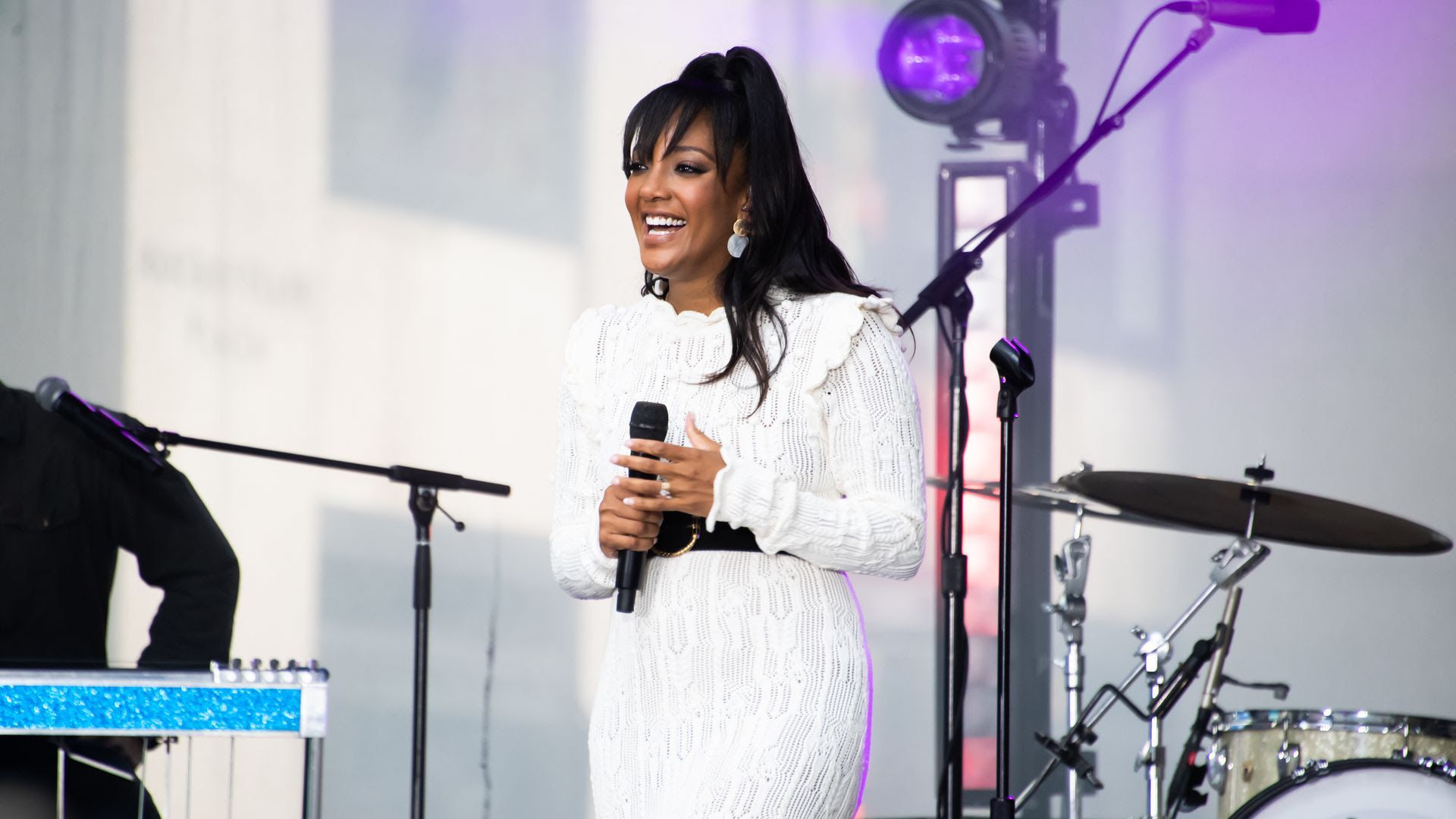Mickey Guyton singing on stage in a white dress 