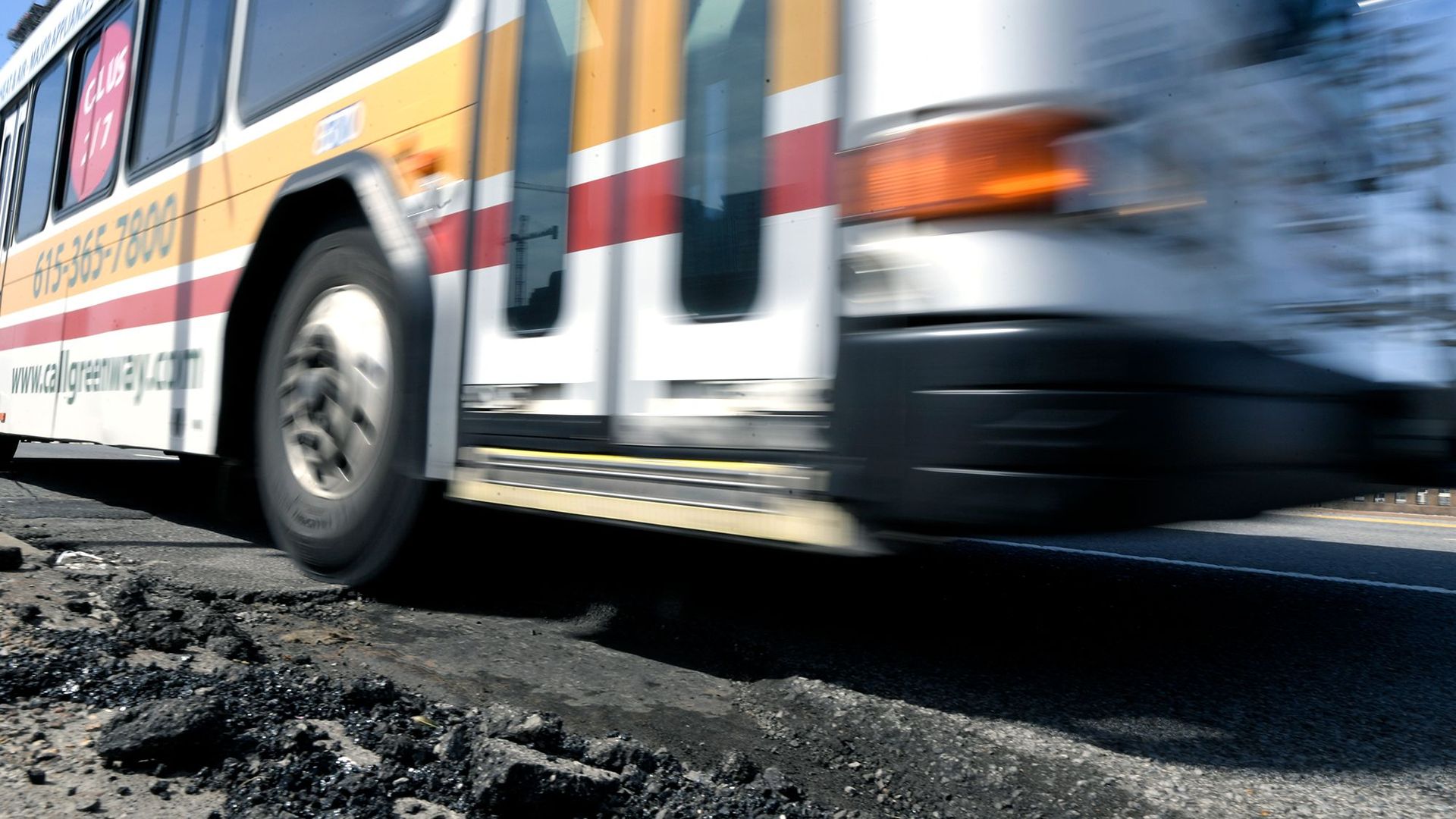 A bus driving over a pothole.