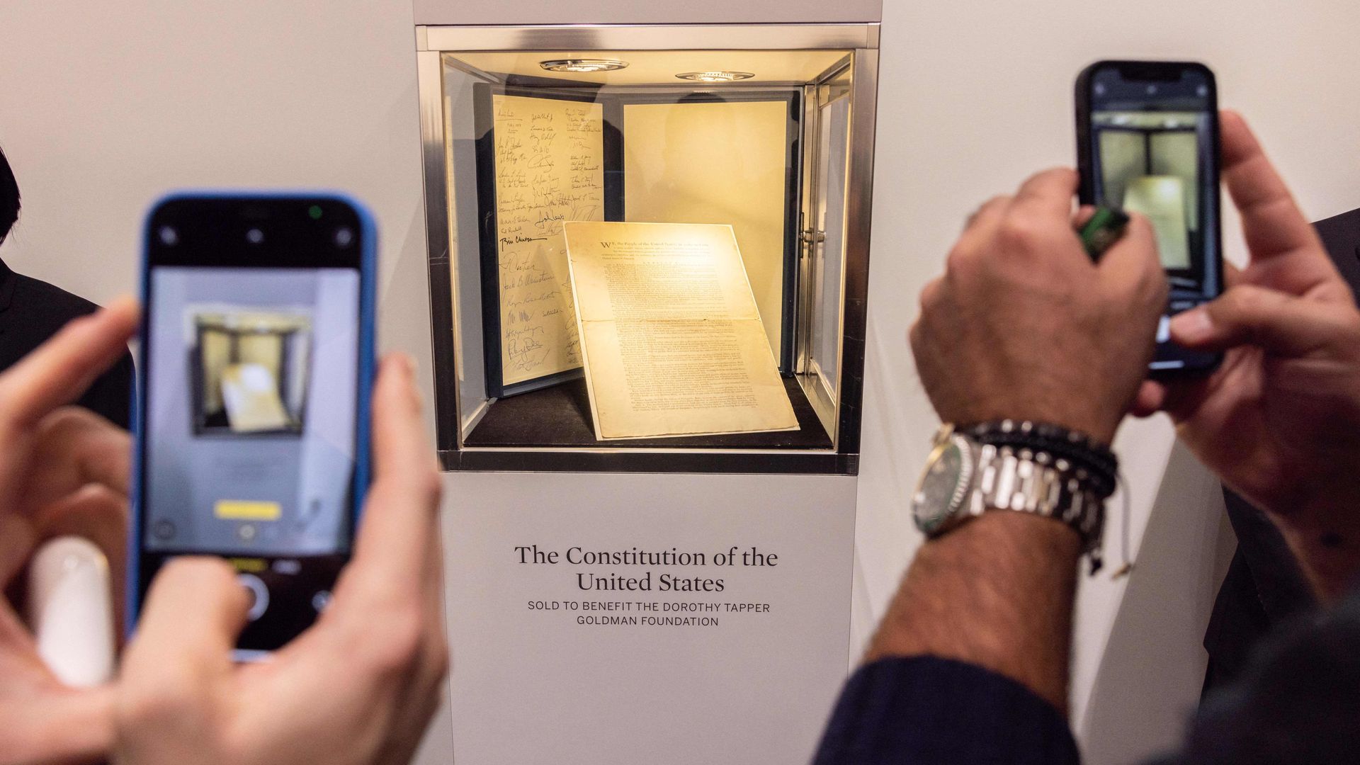 People take pictures of the first printing of the United States Constitution during an auction at Sotheby's auction house
