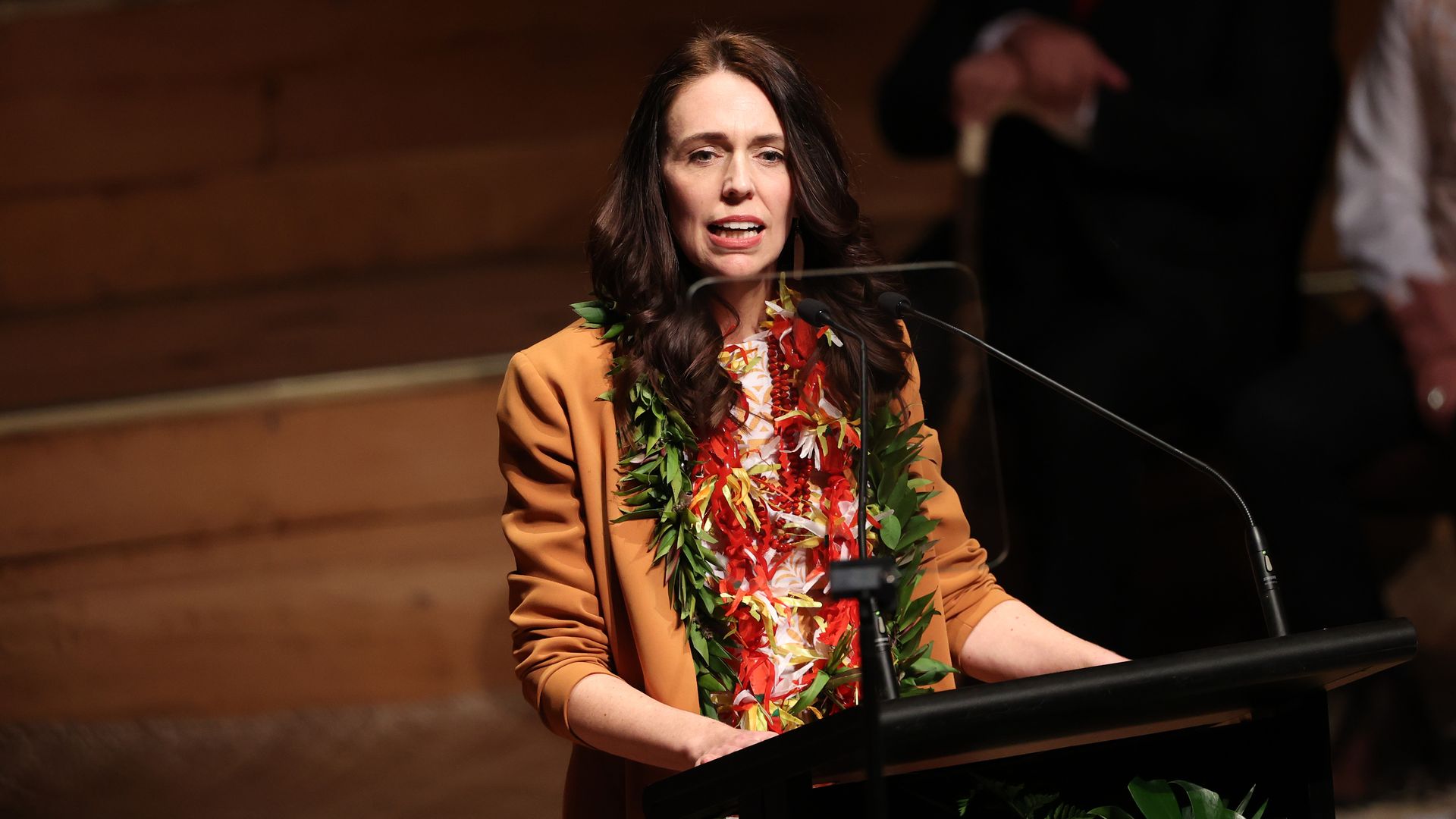 Jacinda Arden, with traditional wreaths around her neck, speaks at a podium