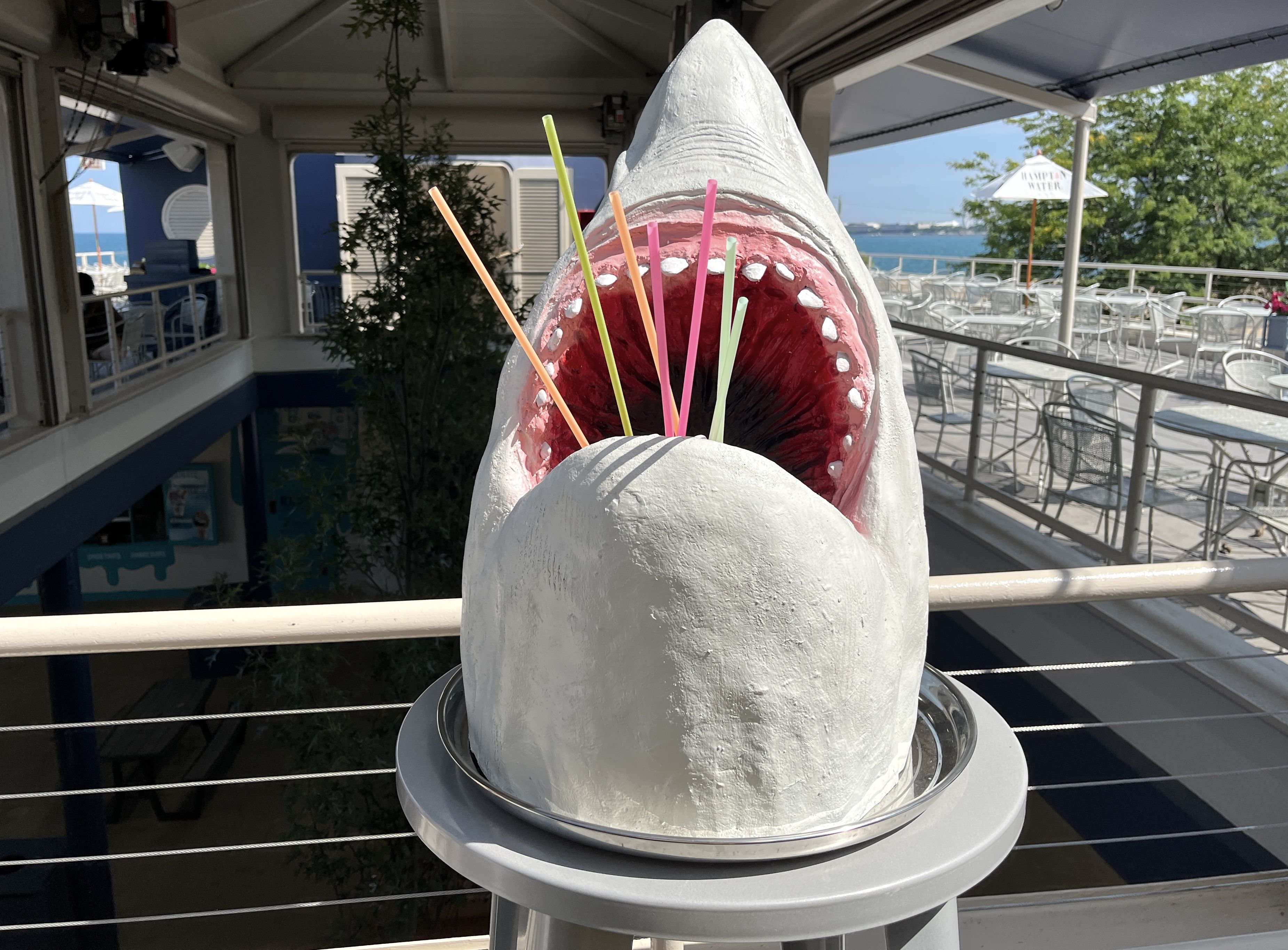 Fake shark head with straws sticking out of its open mouth.