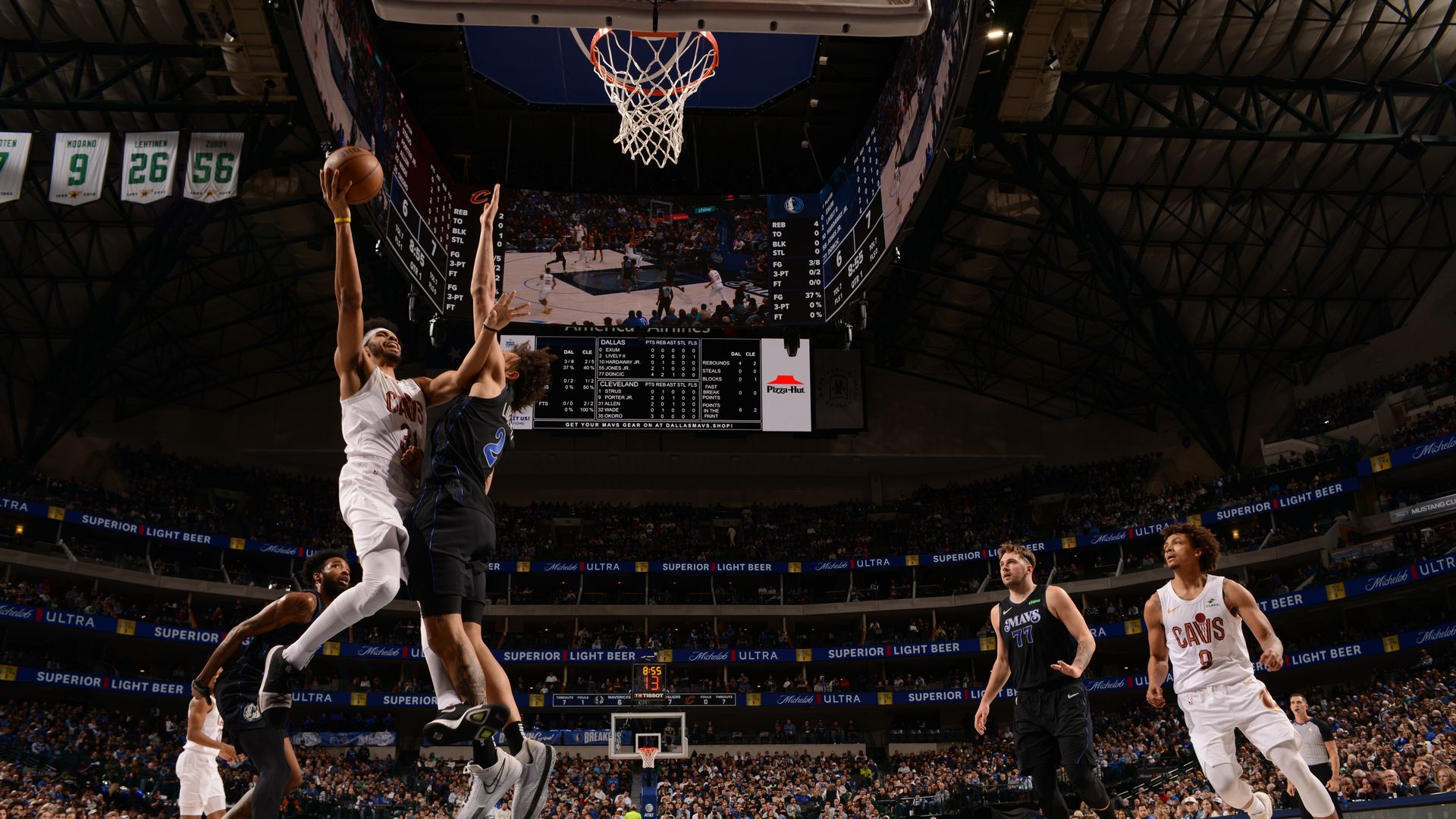 Jarrett Allen (white) soars to the rim against a Dallas Mavericks defender (navy) 