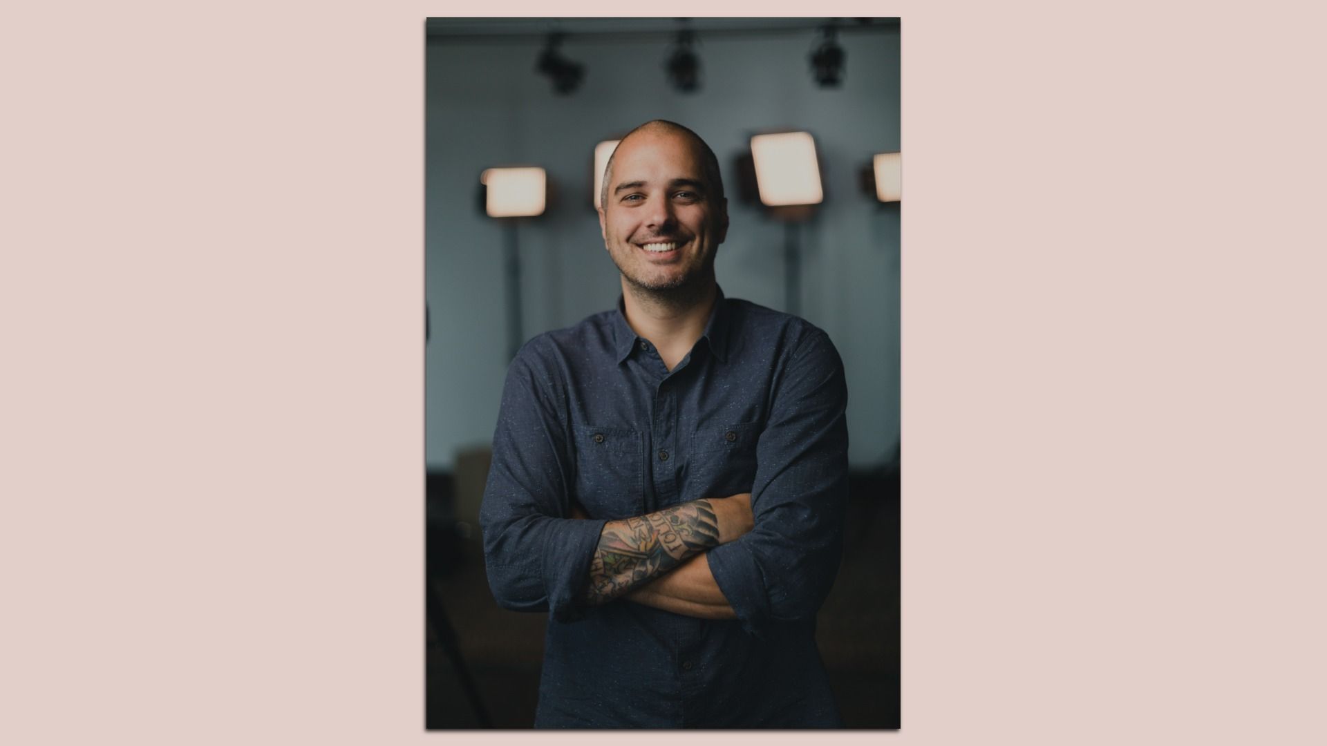 Portrait of a Philly filmmaker Colin Comstock with folded arms, wearing a navy blue button-down shirt. 