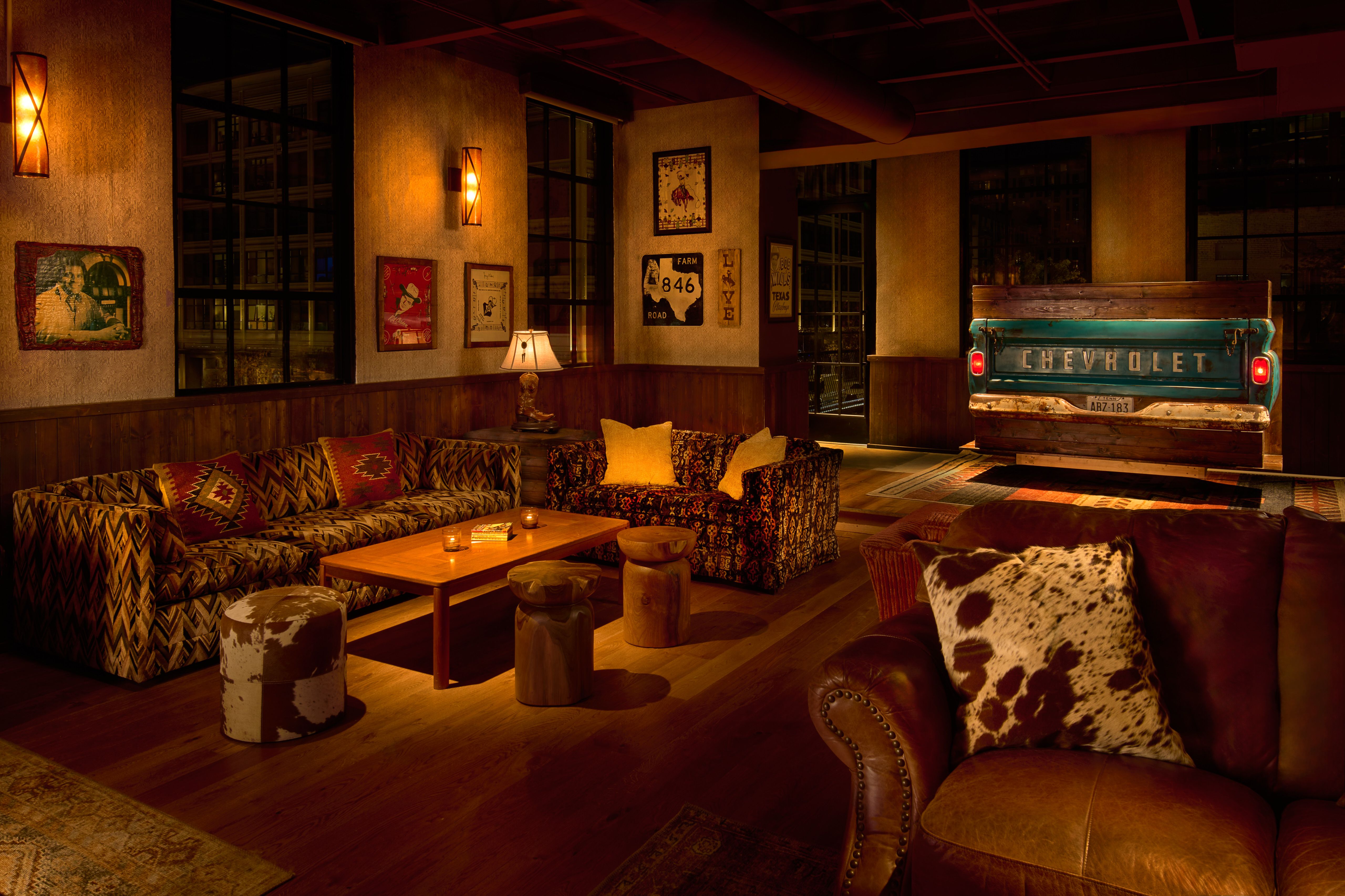 A dimly lit room with cowhide pillows and a Chevrolet car turned DJ booth 