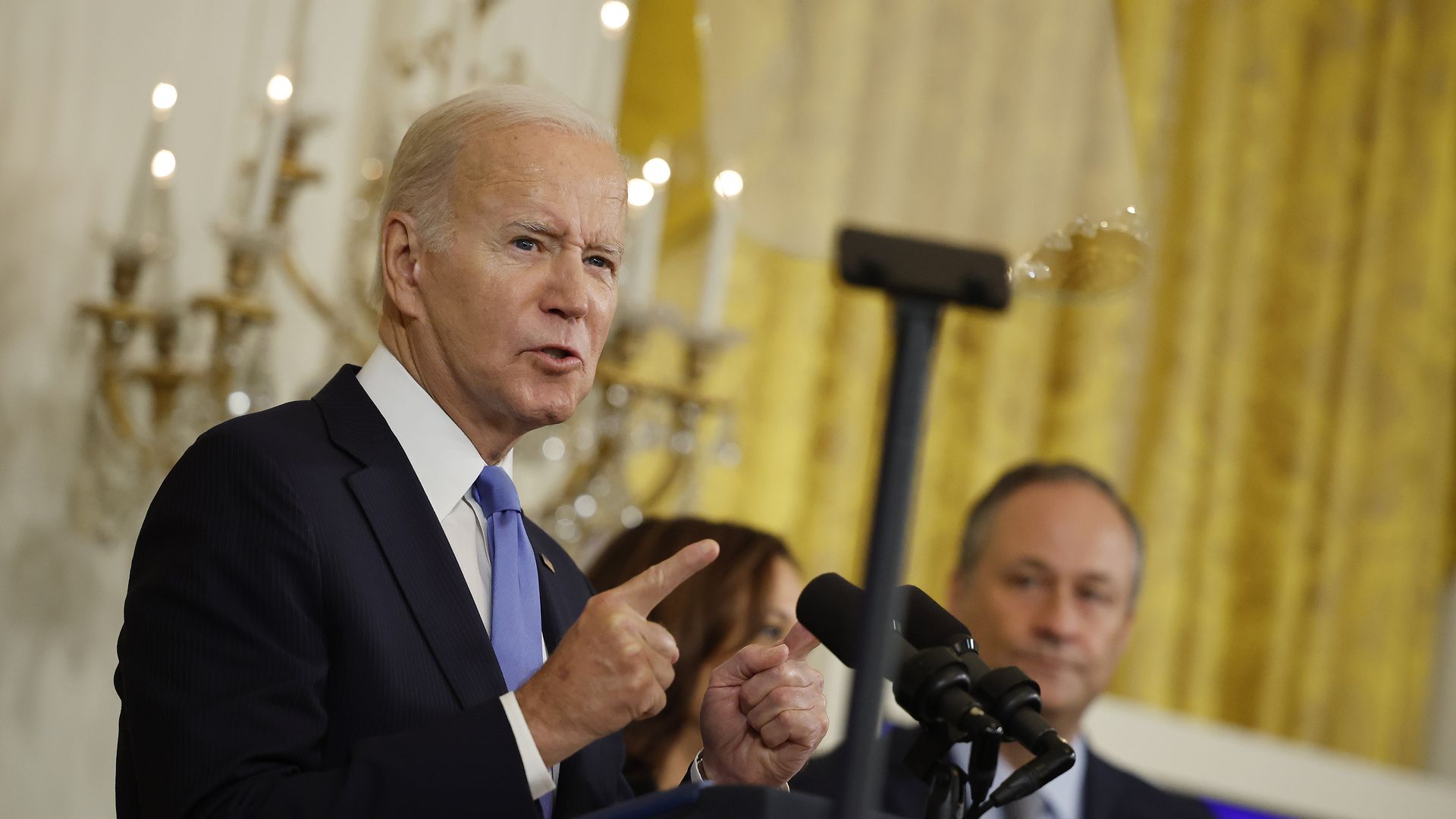 Photo of Joe Biden speaking fro a podium while gesturing with one finger