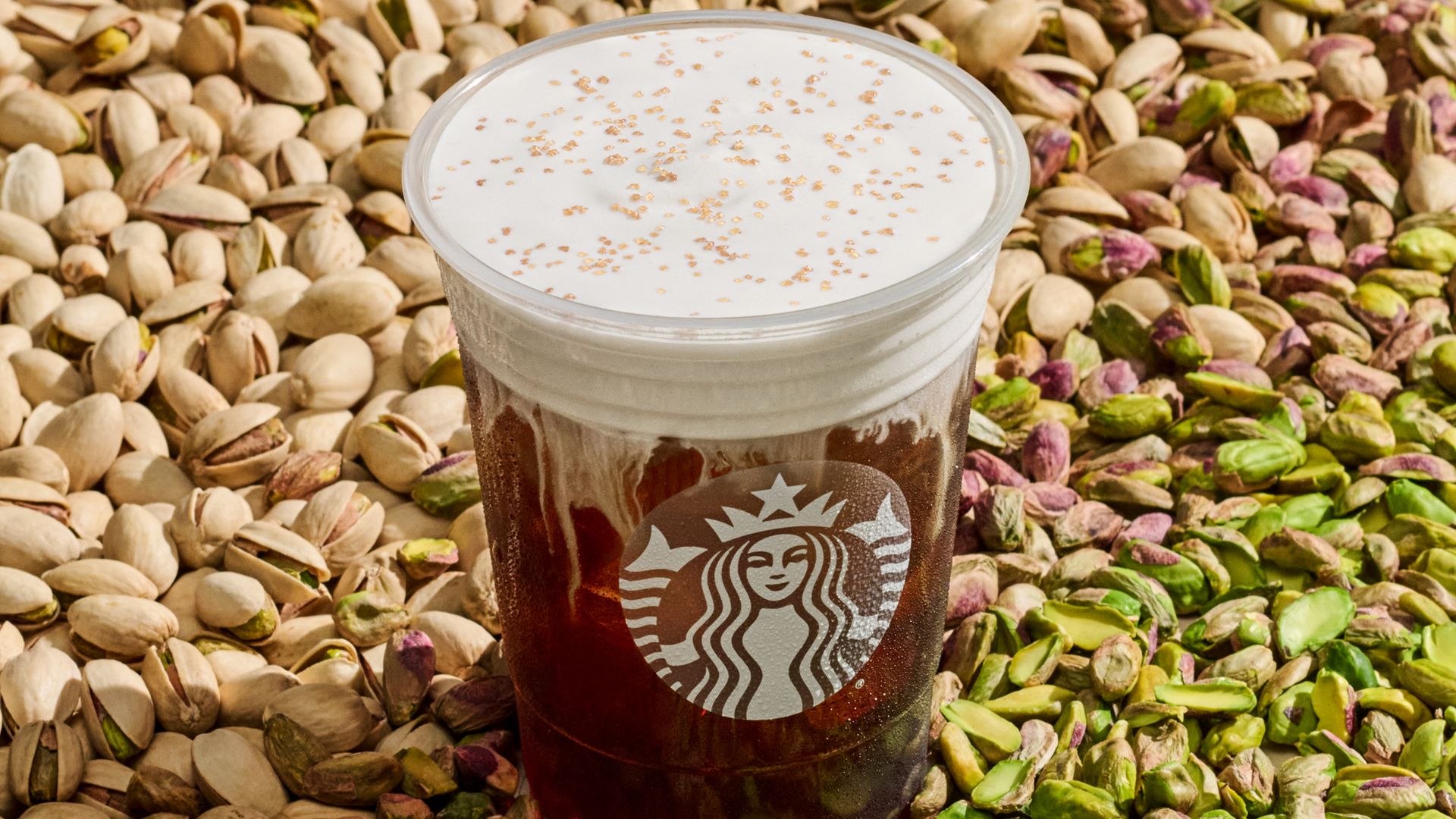 Starbucks plastic cup with cold foam on top of pistachio nuts