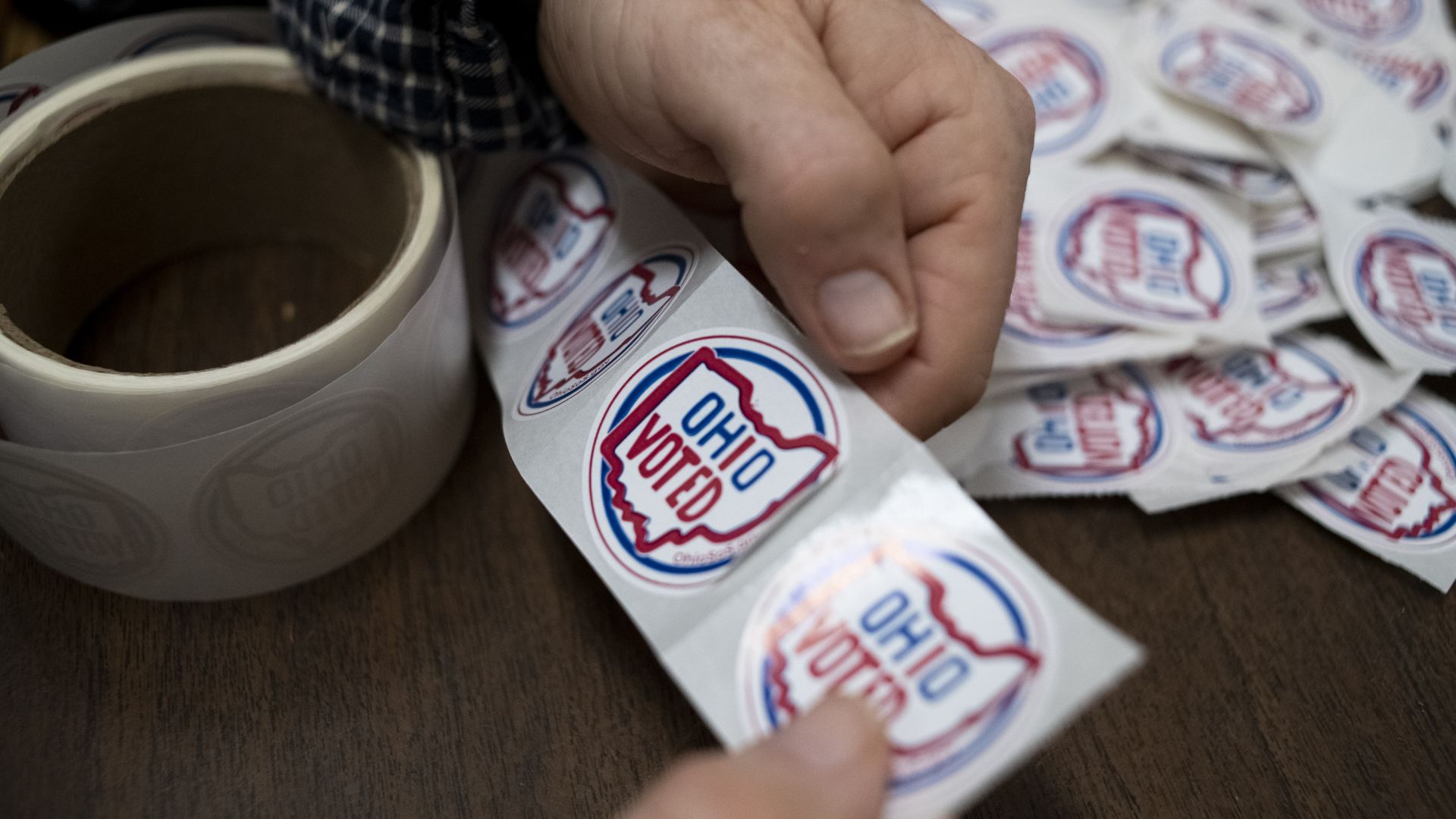 A hand holding a sticker that reads "Ohio voted".