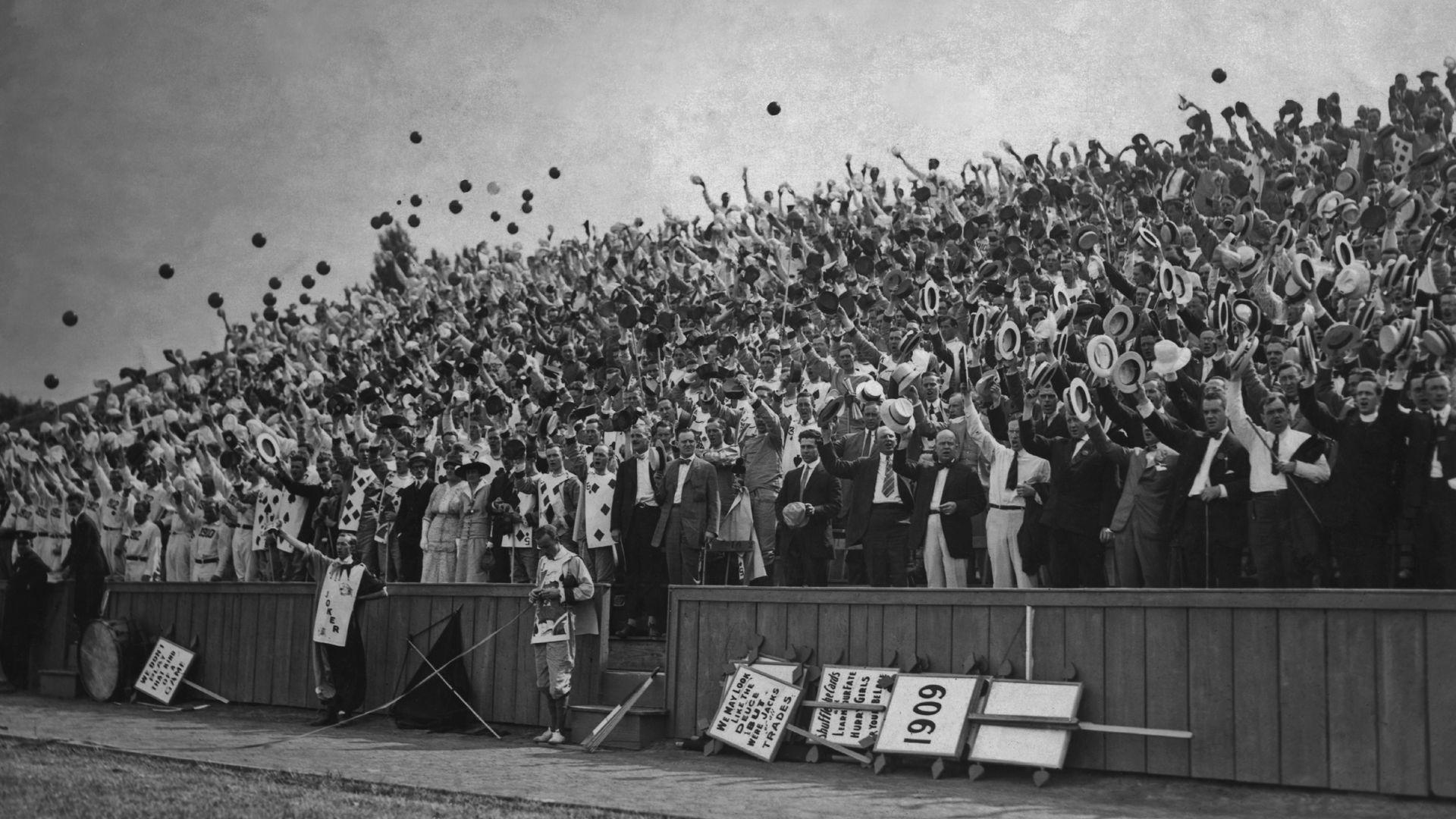 A black and white photo of college graduates throwing caps into the air
