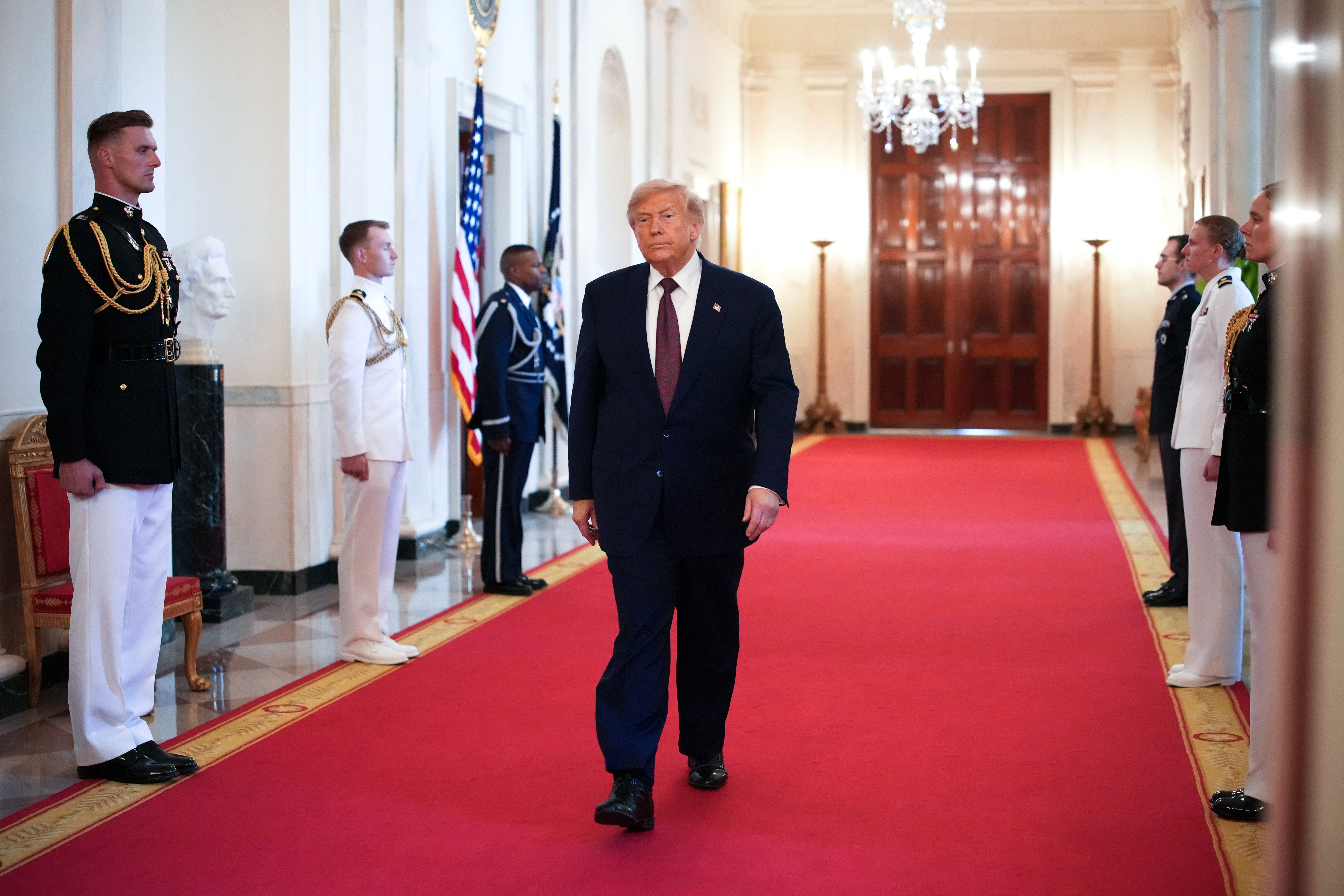 Trump walks down a red-carpeted hallway