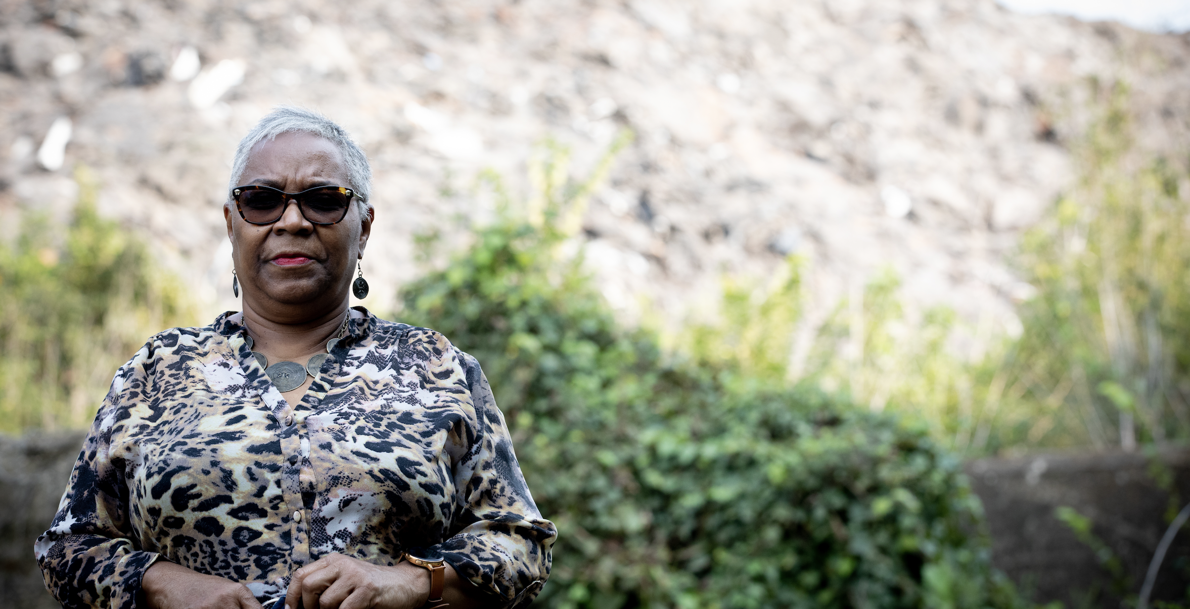 A woman stands in front of a mound of shingles