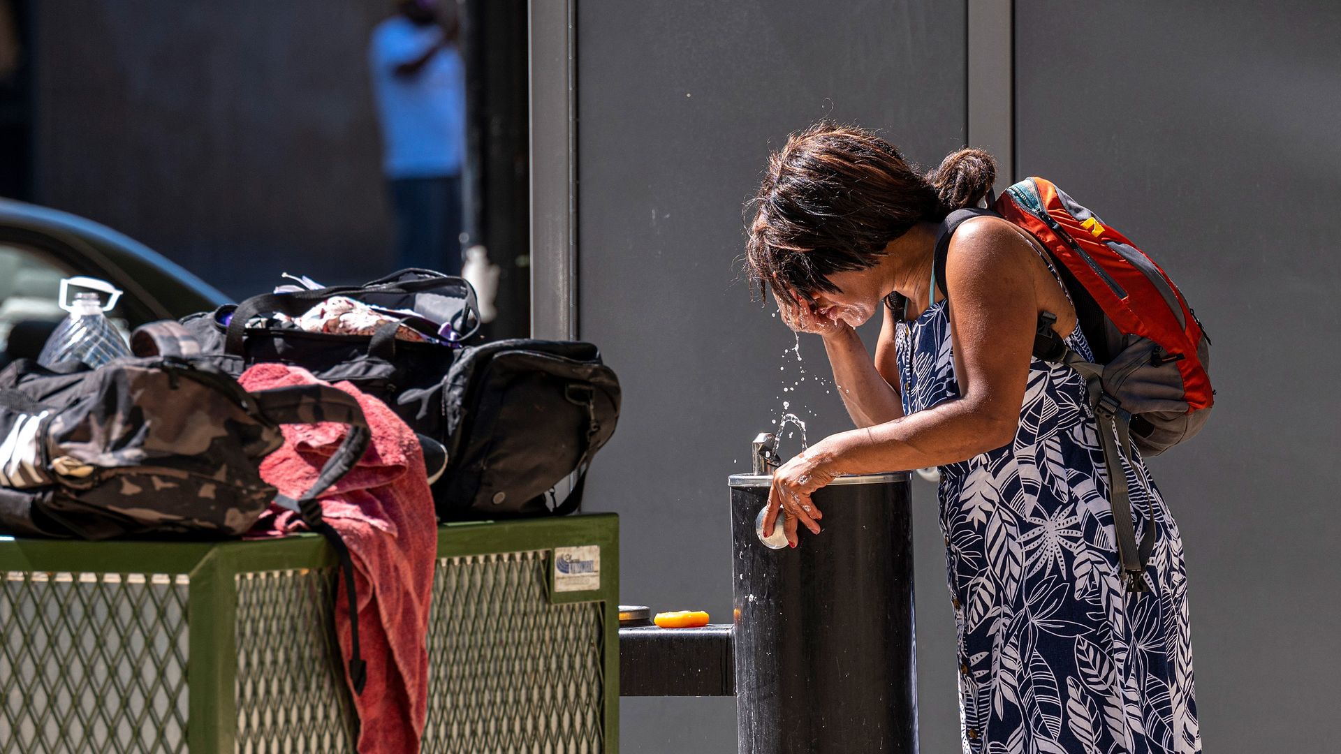 Picture of a woman cooling herself off at a water fountain in California during a heat wave.