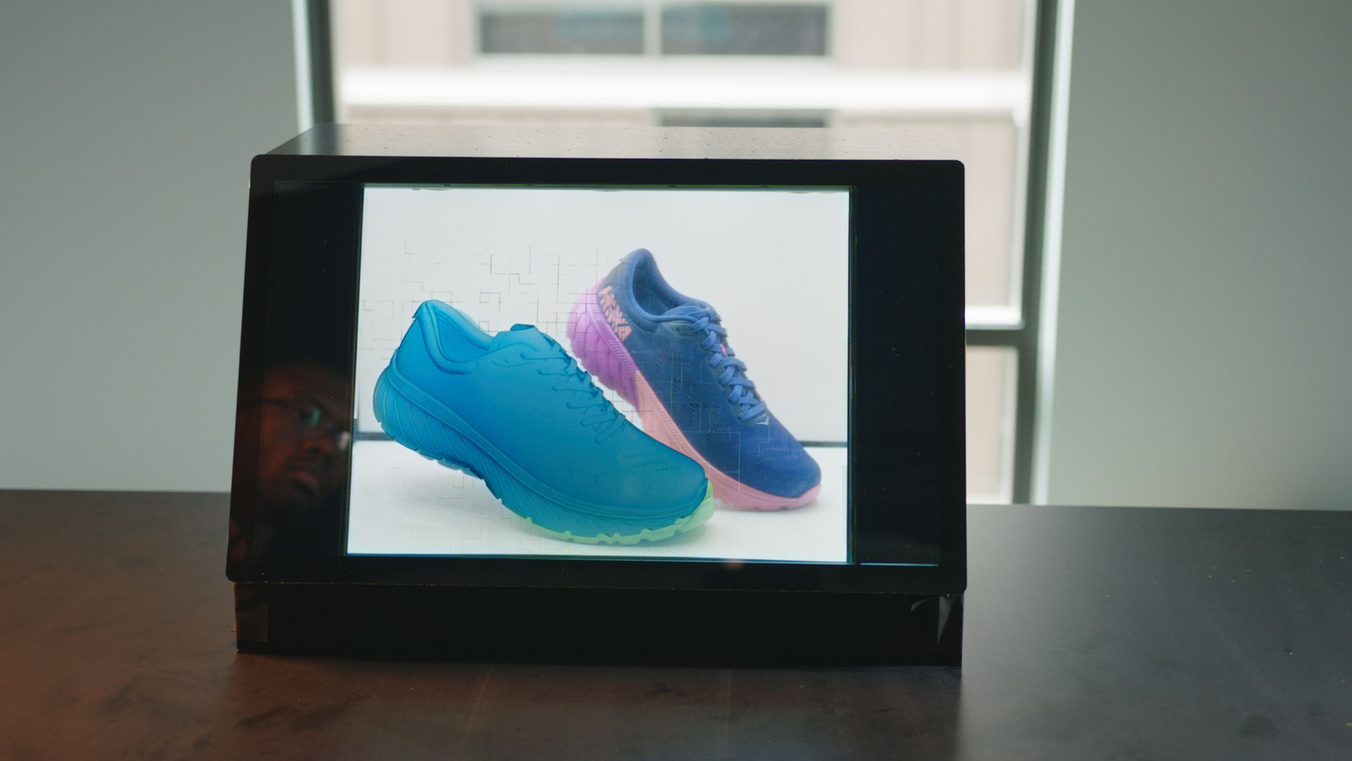 A picture of Project Glasswing, an Adobe-developed transparent display showing a digital shoe in front of a real one.