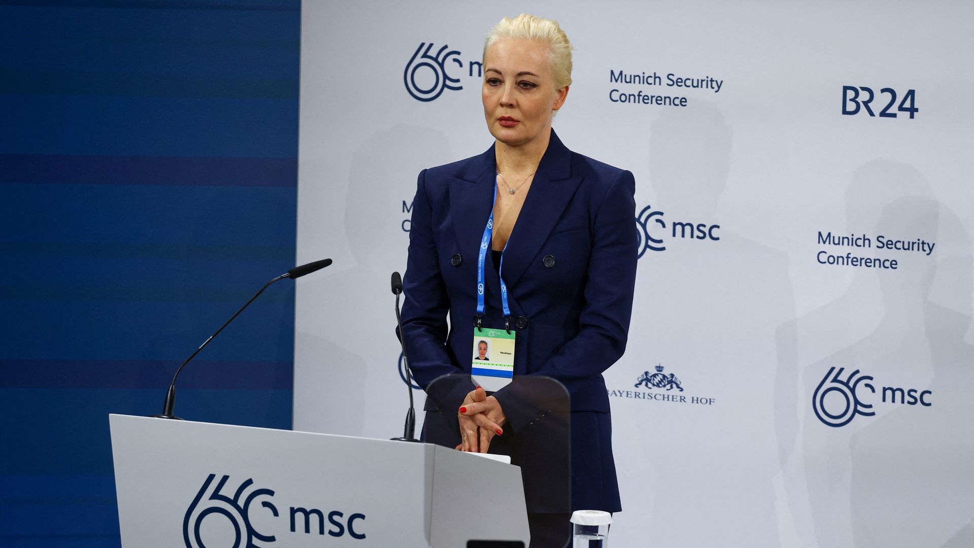 Yulia Navalnaya stands at a lectern with a serious expression