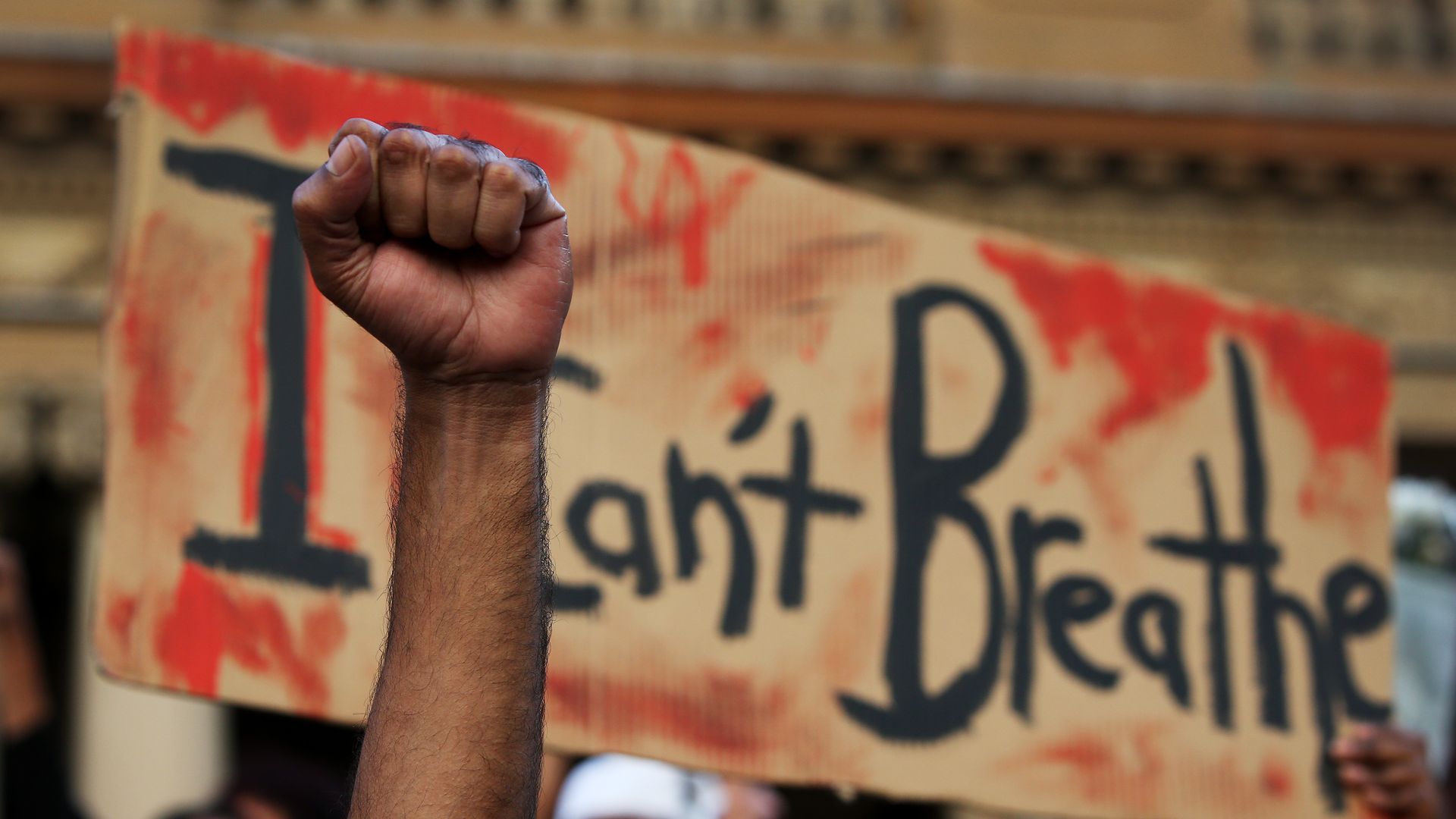 A man holds his fist in the air in front of a placard that reads 'I can't breathe' at Town Hall in solidarity with protests in the United States on June 06, 2020 in Sydney, Australia.