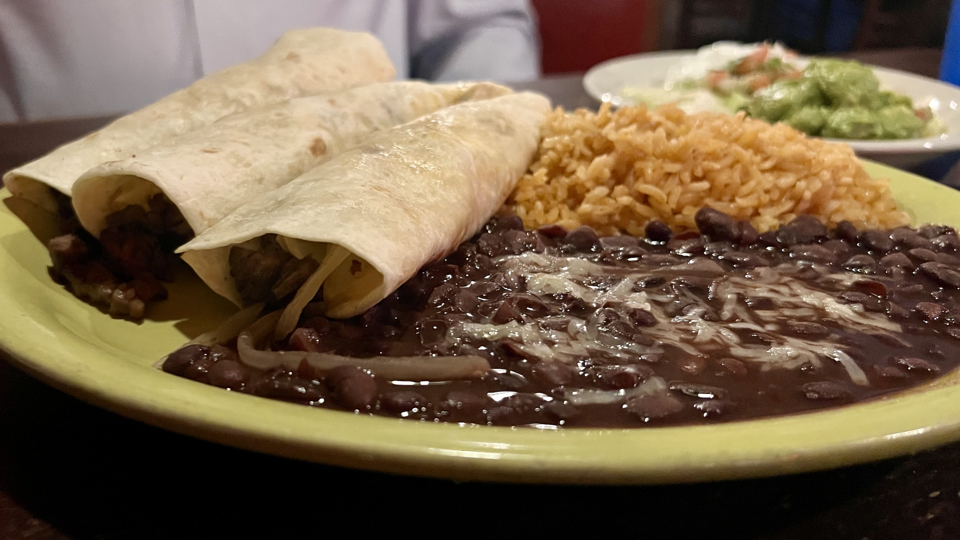 Three steak tacos with a side of rice and beans