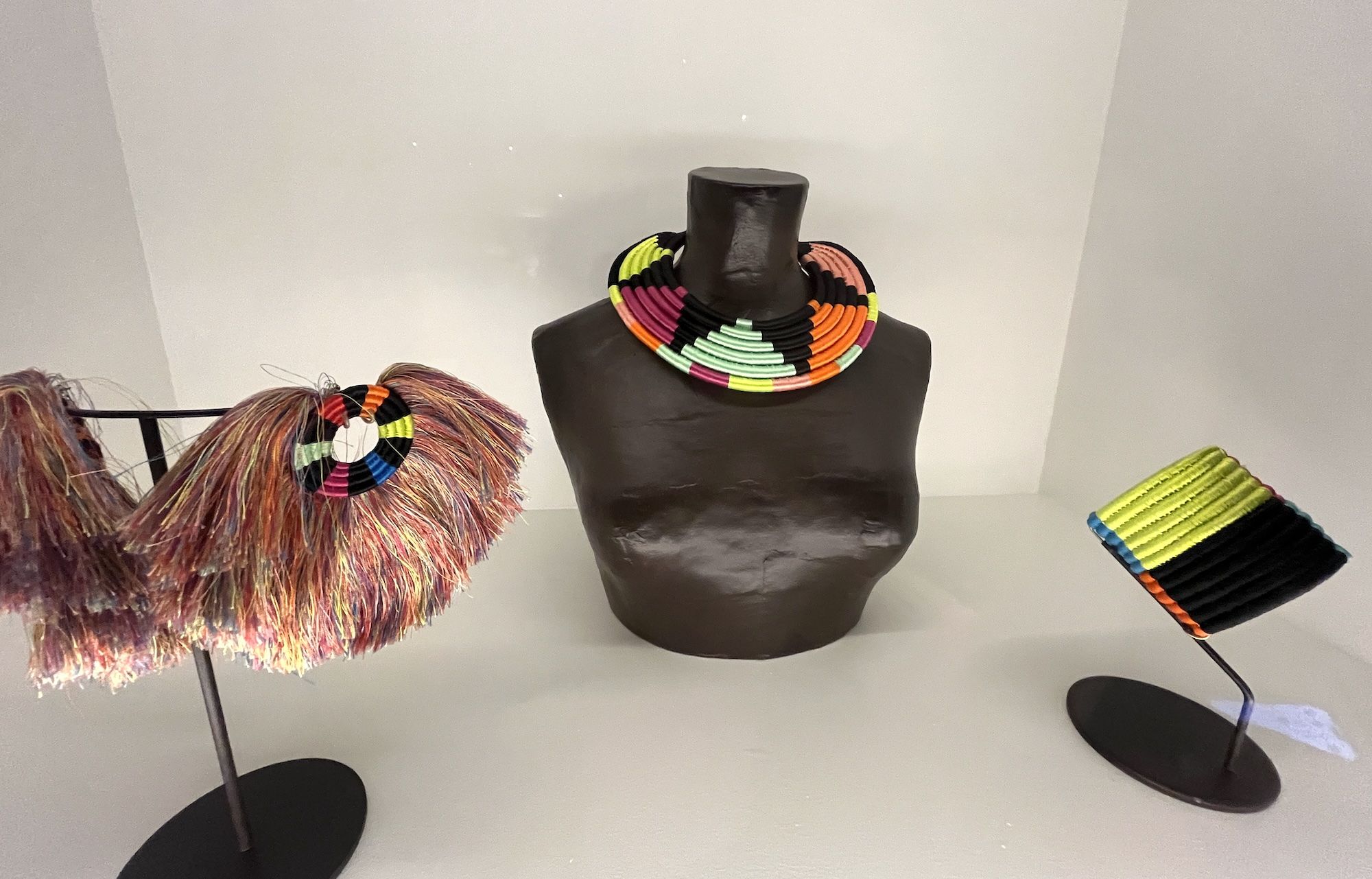 Brightly colored tasseled earrings, a weaved short choker necklace and a weaved bracelet.