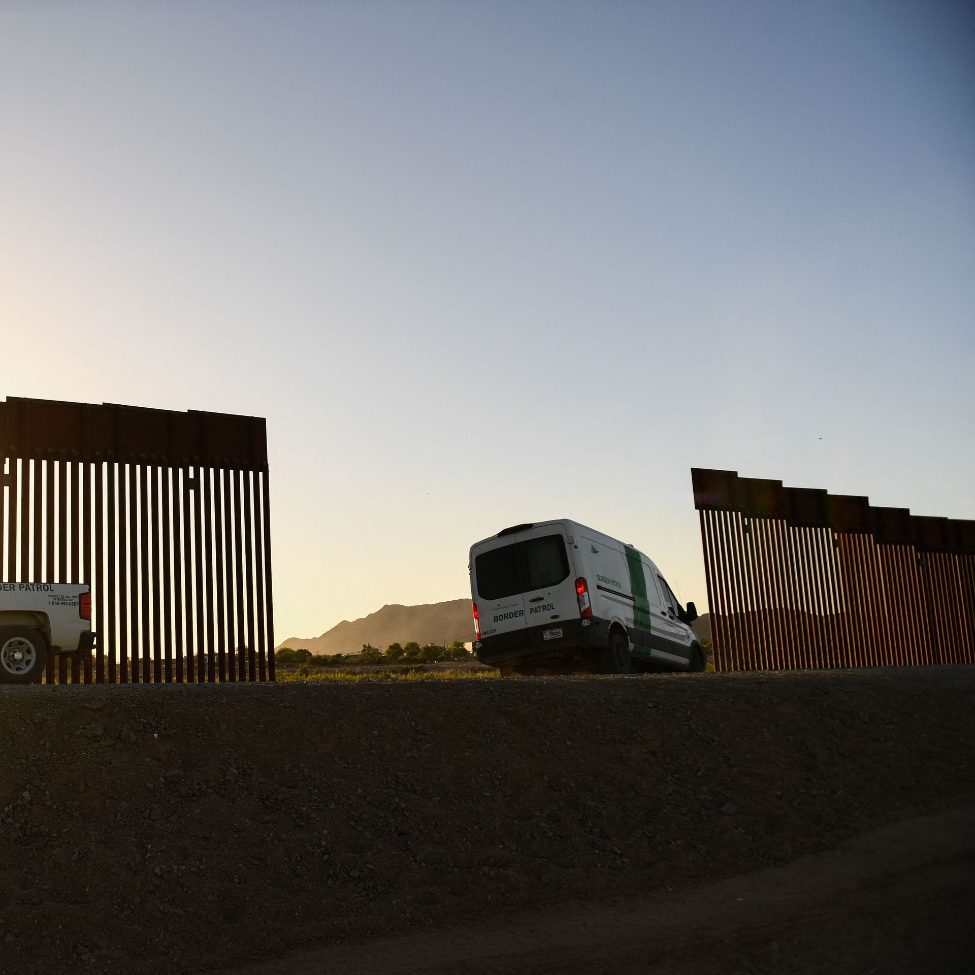 Photo of vans parked beside a gap in the border wall